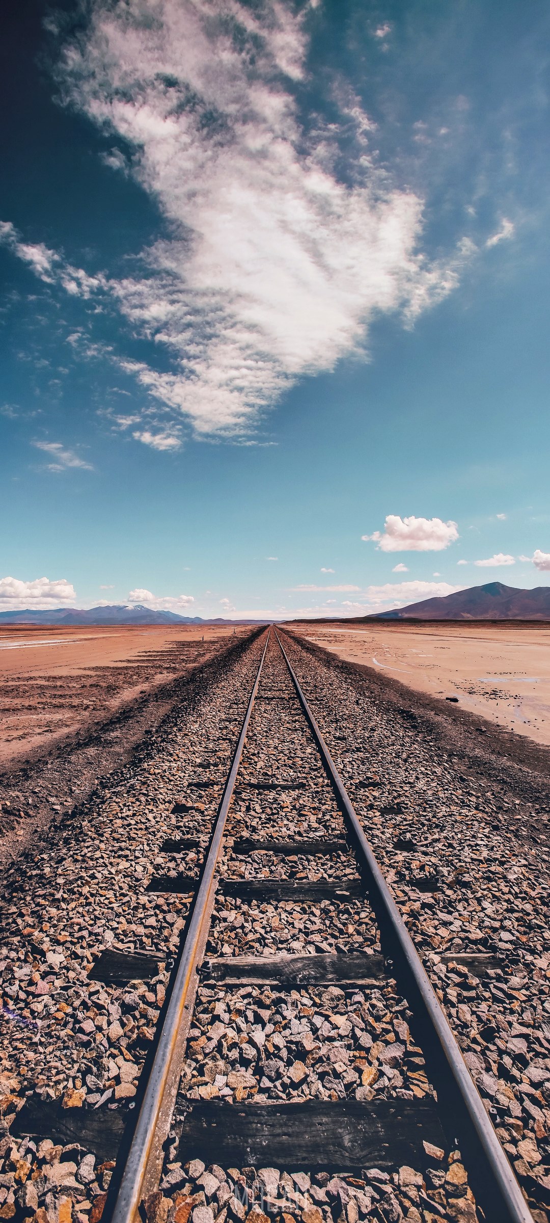 Train tracks in the Bolivian desert under a cloudy sky HD Phone Wallpaper