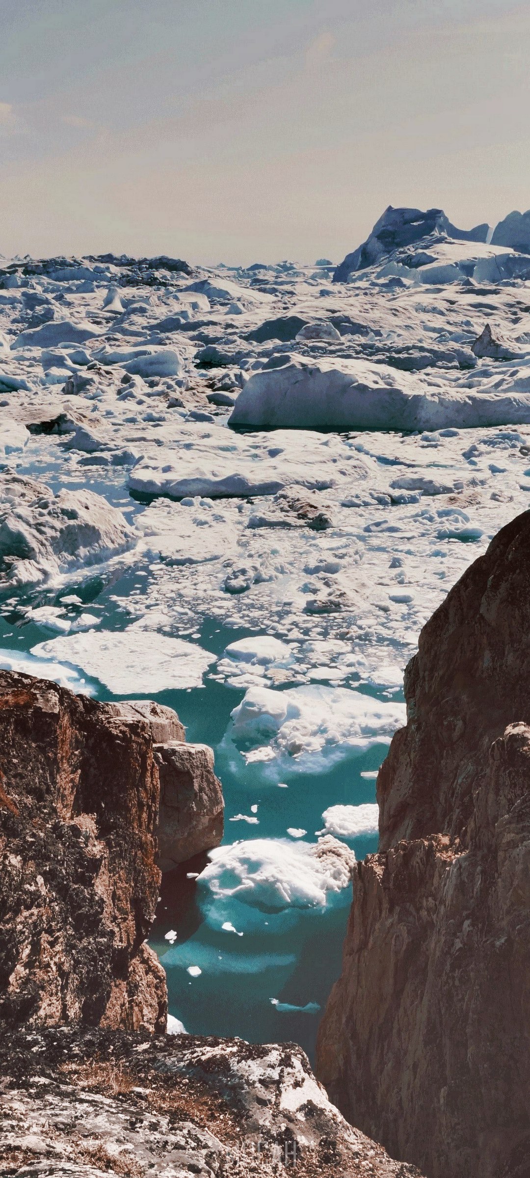 Icebergs floating in a glacial lagoon with rocky cliffs HD Phone Wallpaper