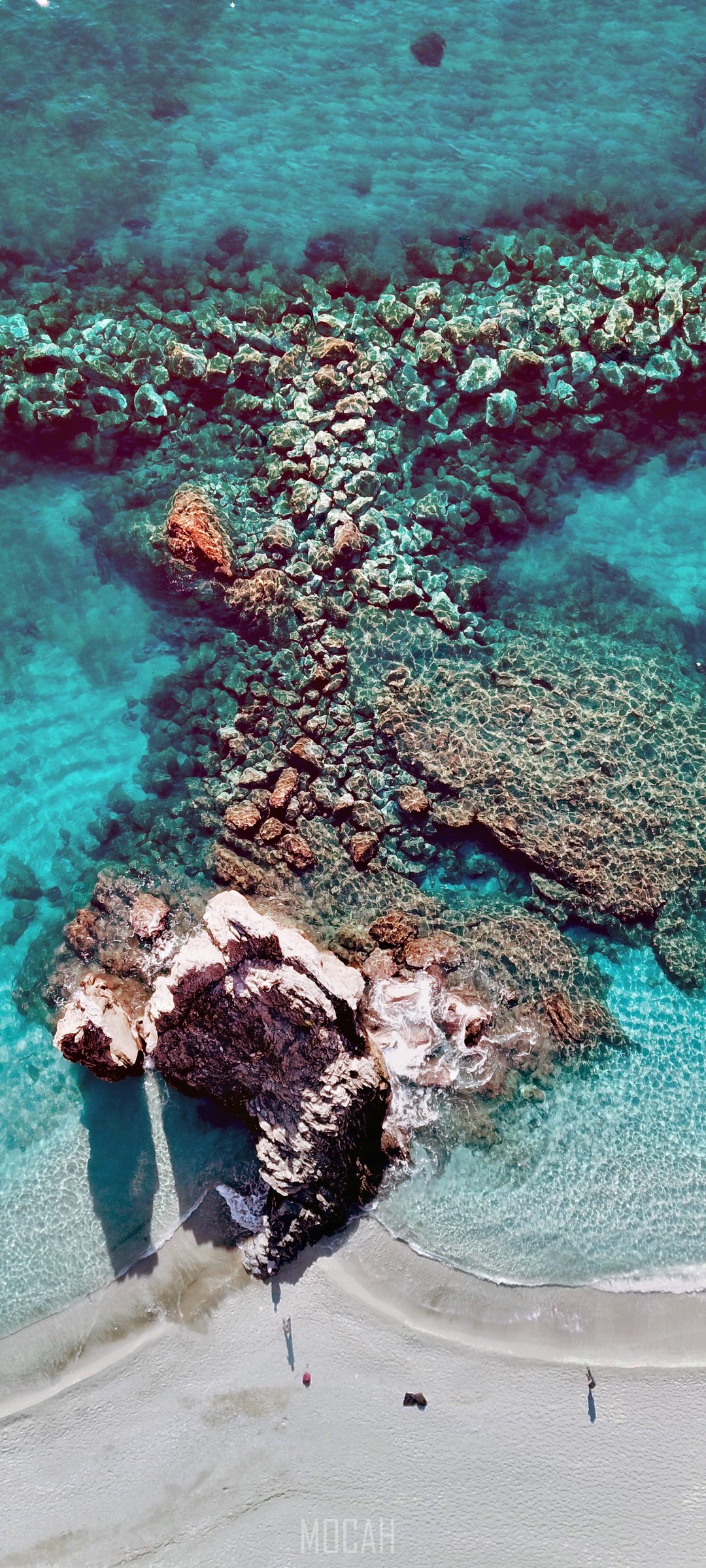Aerial view of a rocky coastline with crystal blue water HD Phone Wallpaper