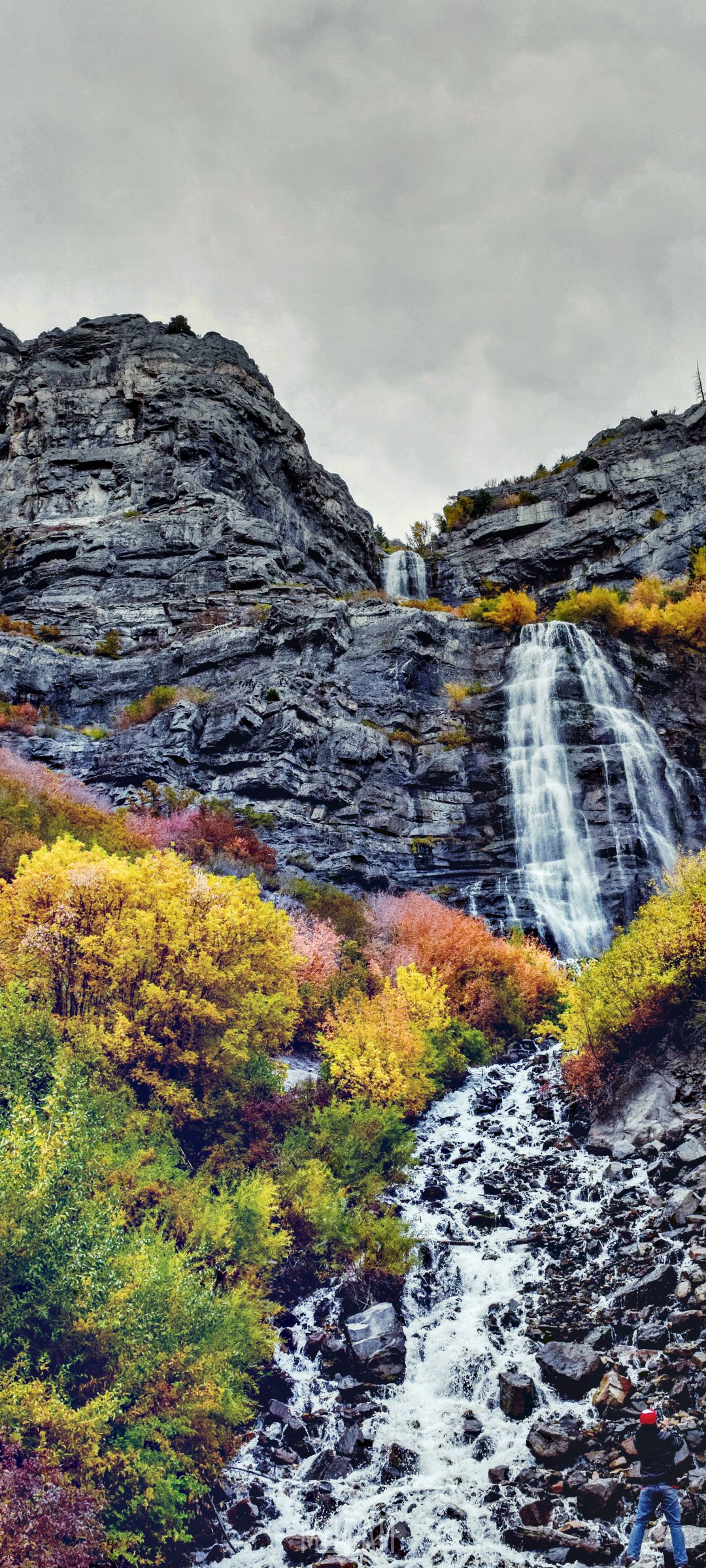 Waterfall cascading down rocky mountain with autumn foliage HD Phone Wallpaper