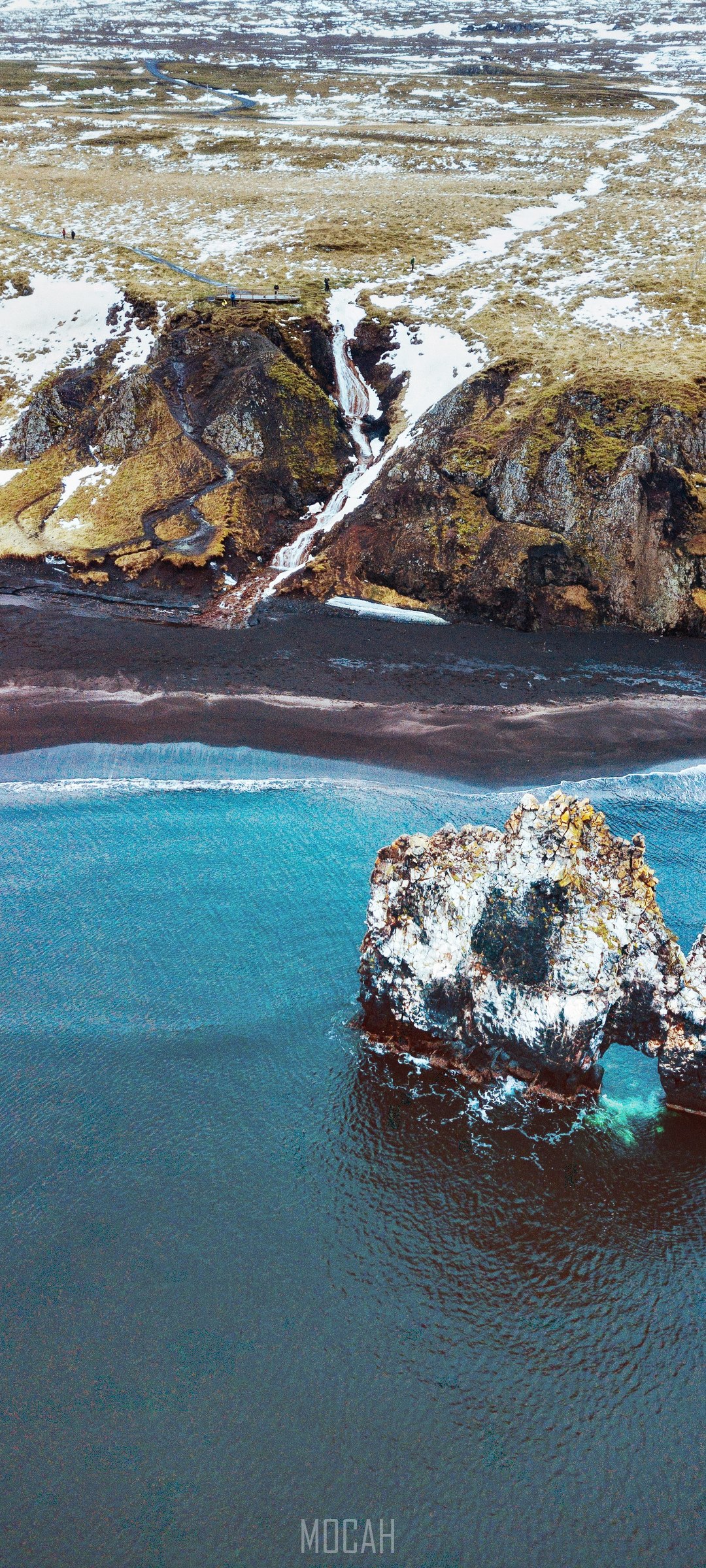 Coastal rock arch with waterfall and black sand beach HD Phone Wallpaper