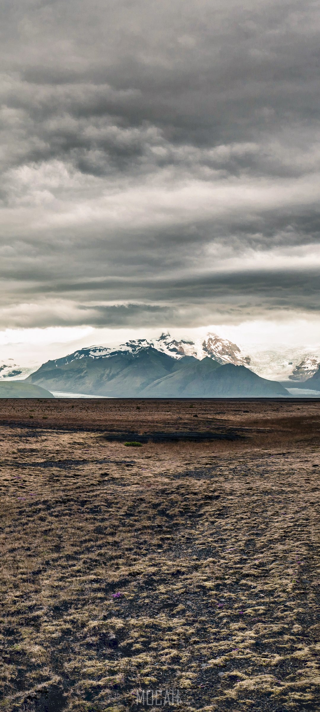 Snow-capped mountains over a barren field under a cloudy sky HD Phone Wallpaper