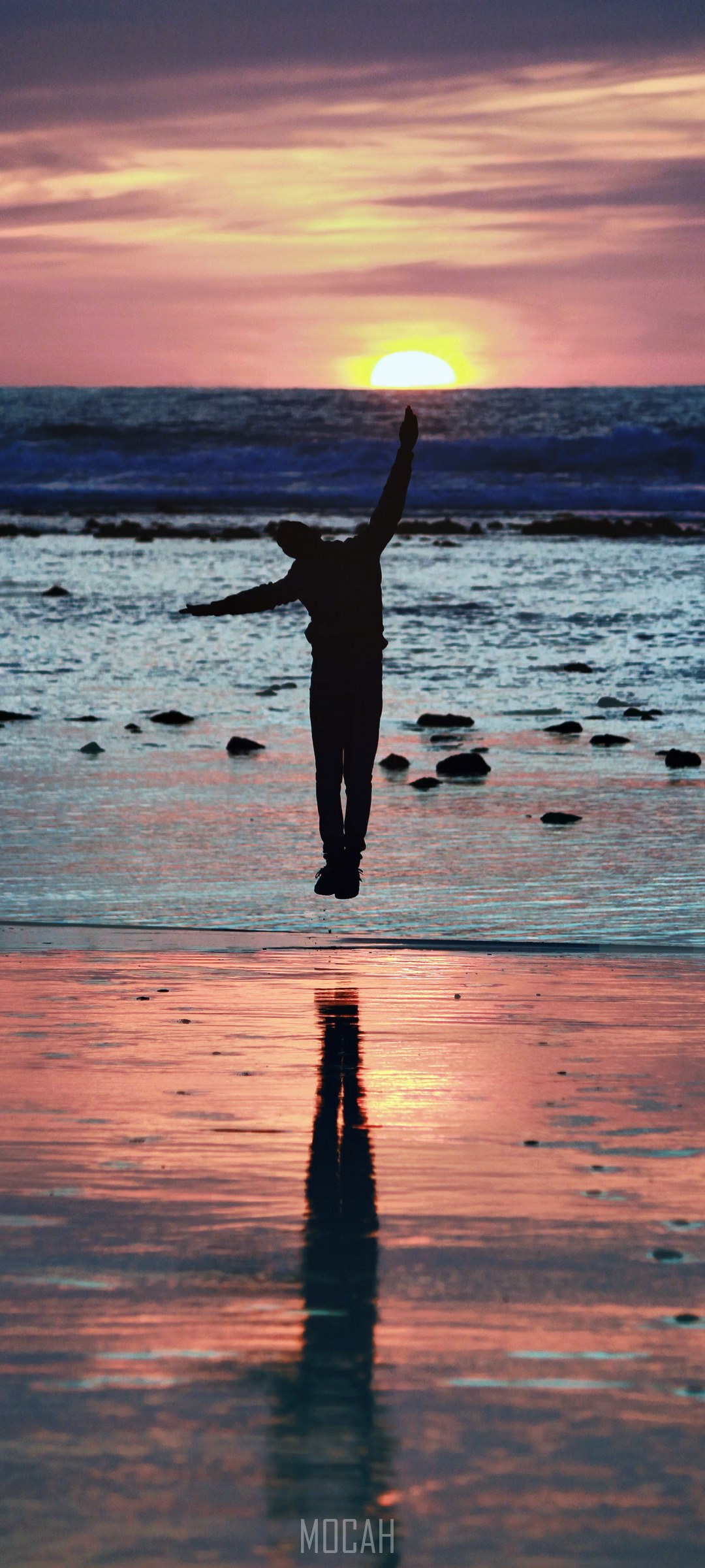 Silhouette of a person jumping on a beach at sunset HD Phone Wallpaper