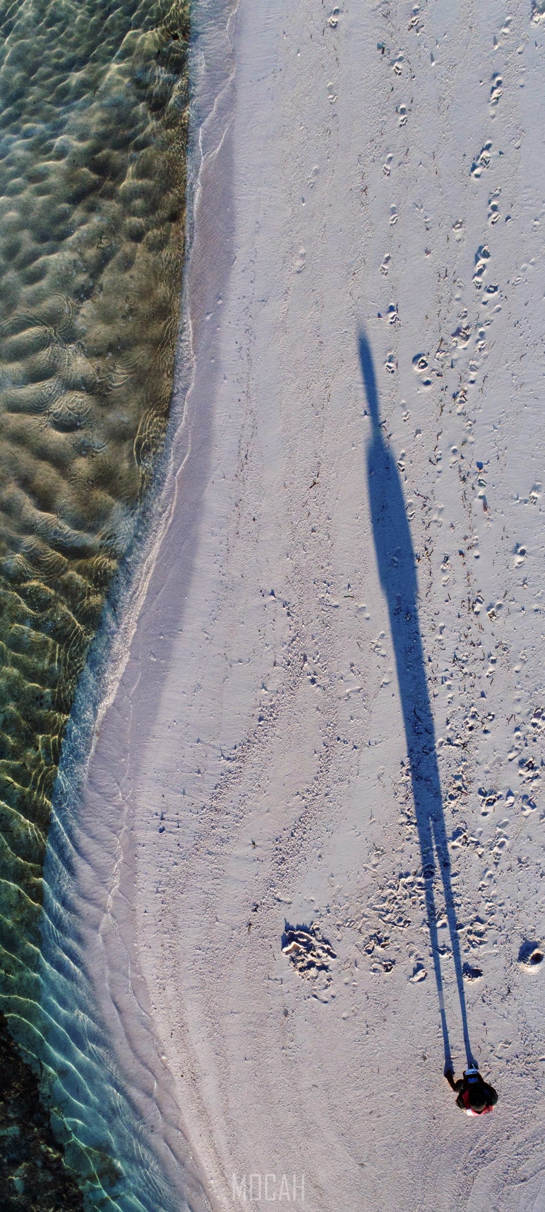 Person walking on a sandy beach with long shadow HD Phone Wallpaper
