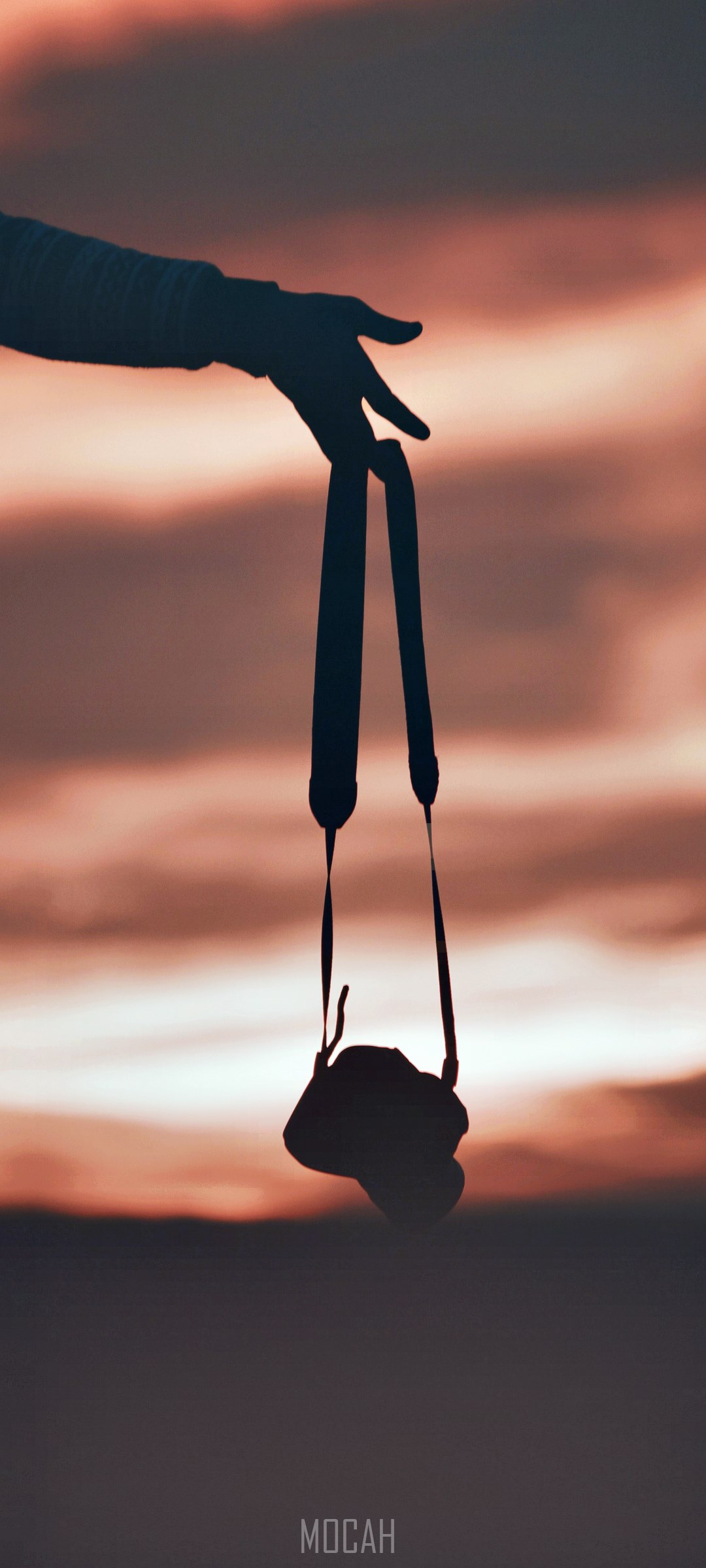 Silhouette of a hand holding a camera against a sunset sky HD Phone Wallpaper