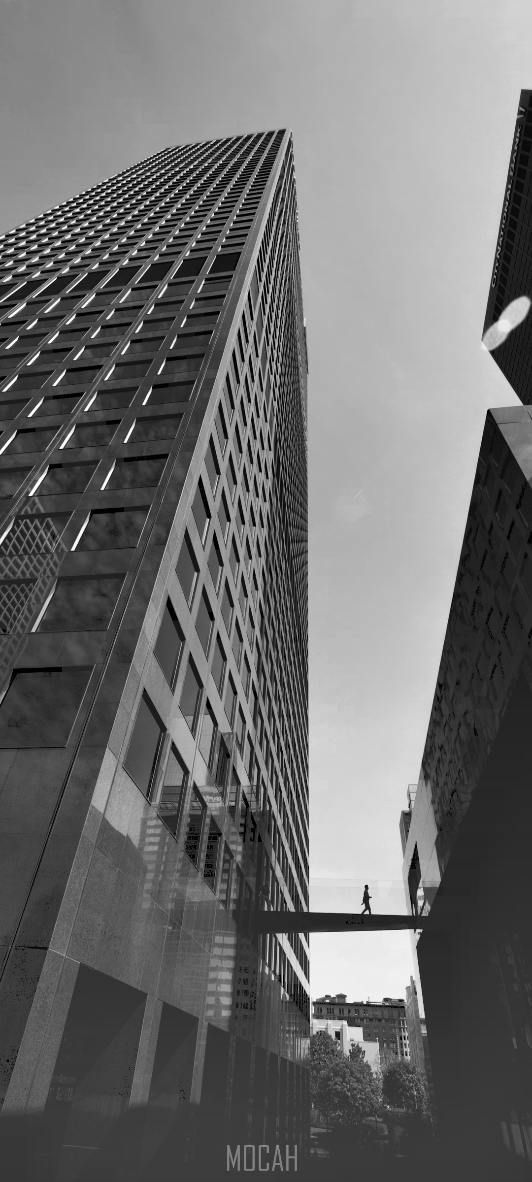 Silhouette of a person walking on a skybridge between skyscrapers HD Phone Wallpaper