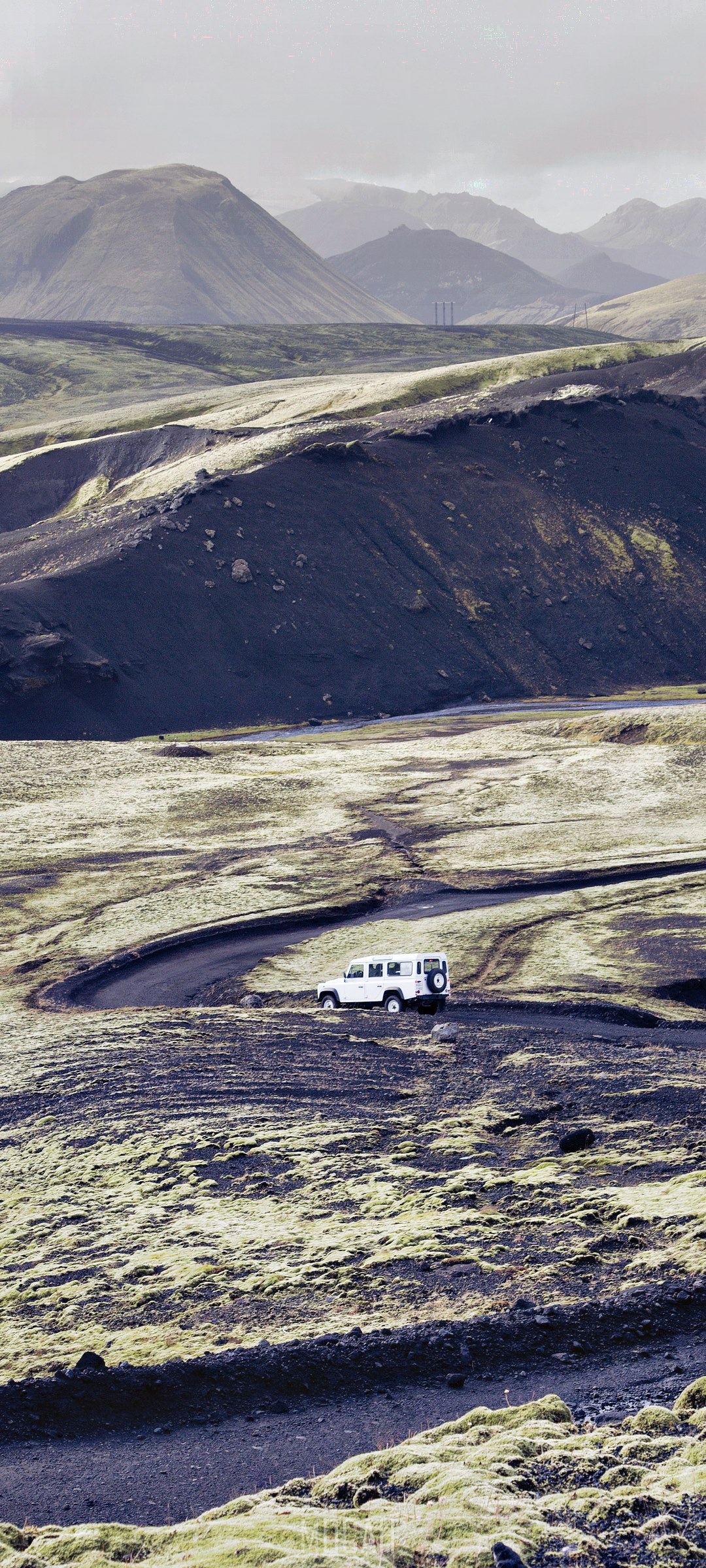 White SUV on a zigzagging dirt road in a mountainous landscape HD Phone Wallpaper