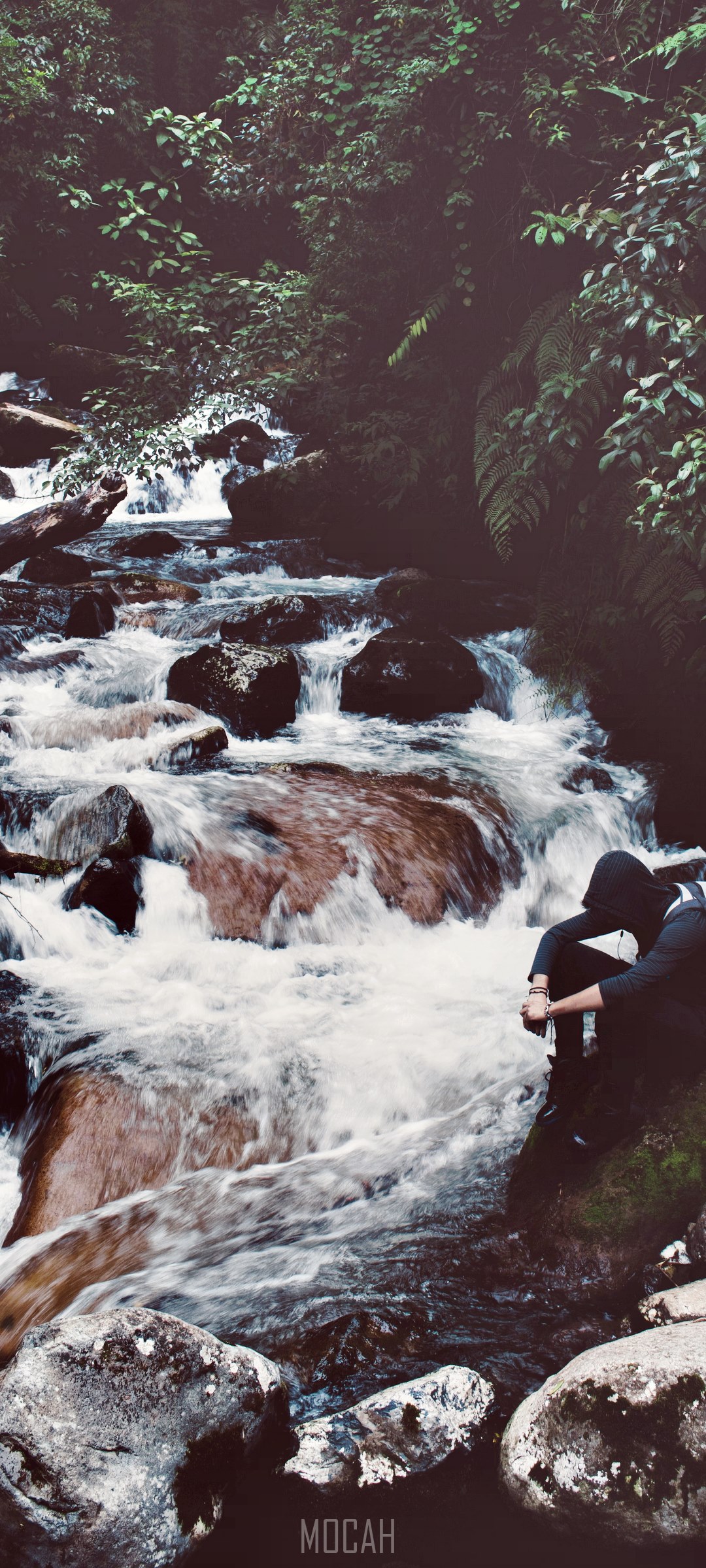 Person sitting by a waterfall in a forest HD Phone Wallpaper