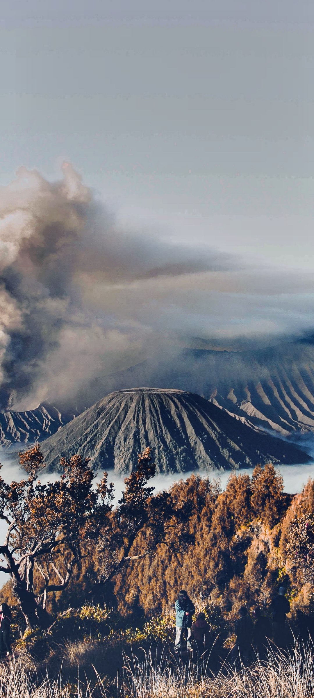 People on mountain slope with smoking volcano HD Phone Wallpaper