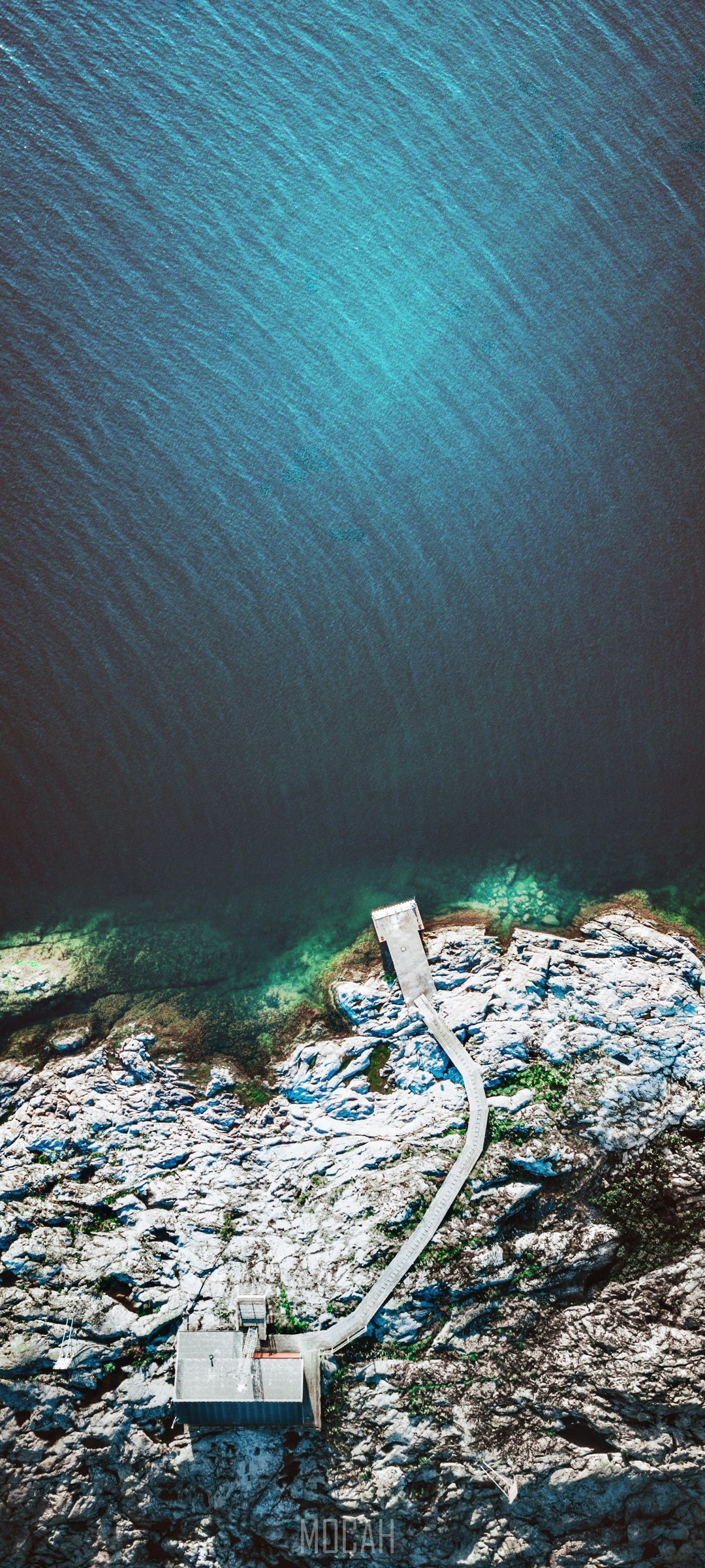 Aerial view of a pier and cabin on a rocky shore HD Phone Wallpaper