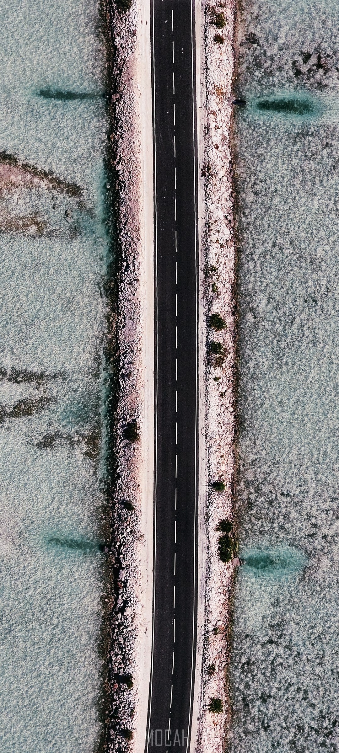 Aerial view of a road through shallow turquoise water HD Phone Wallpaper