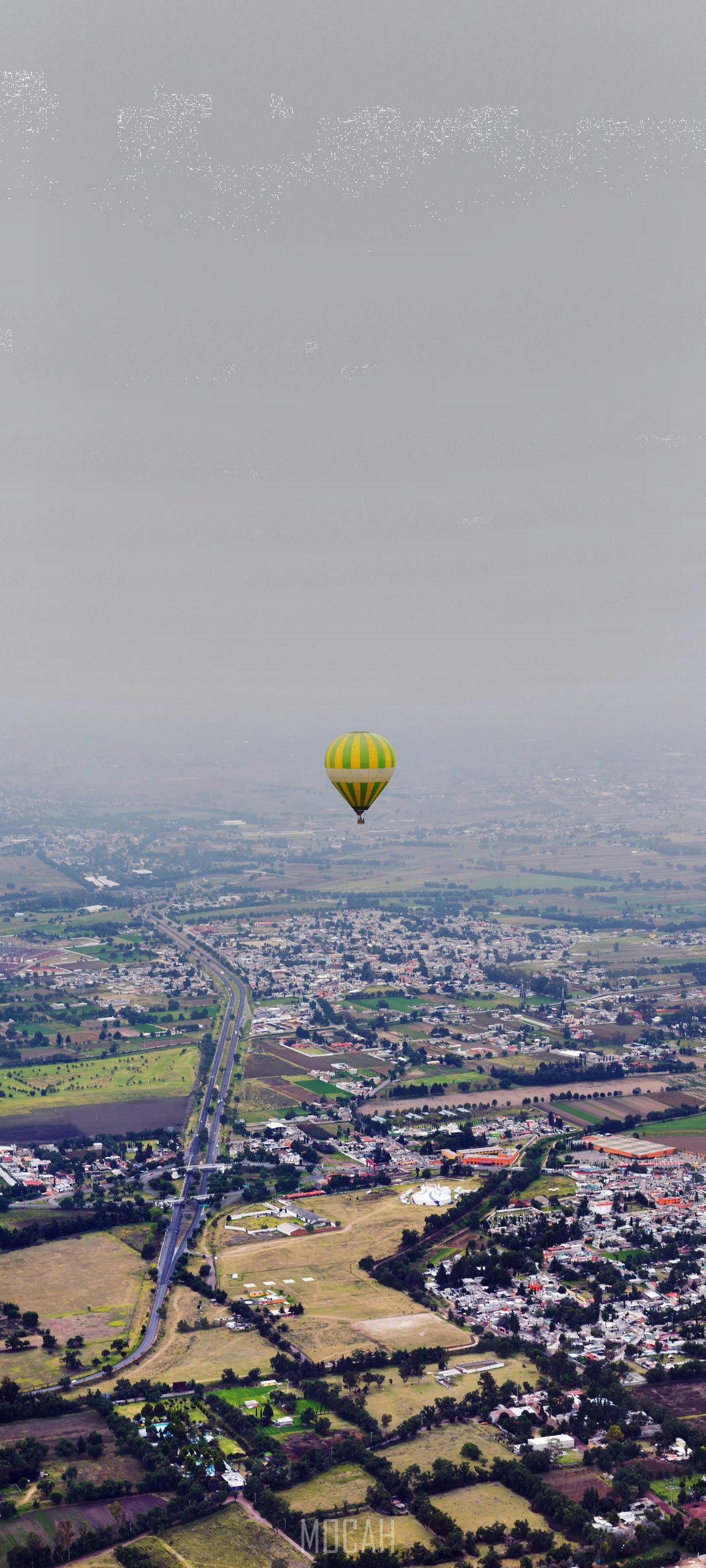 Hot air balloon flying over a city HD Phone Wallpaper