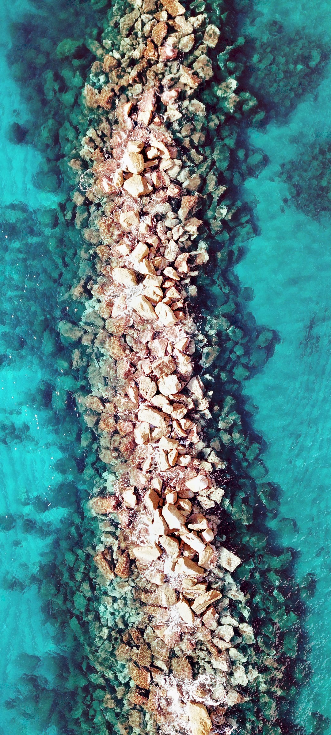 Breakwater made of rocks in turquoise water HD Phone Wallpaper