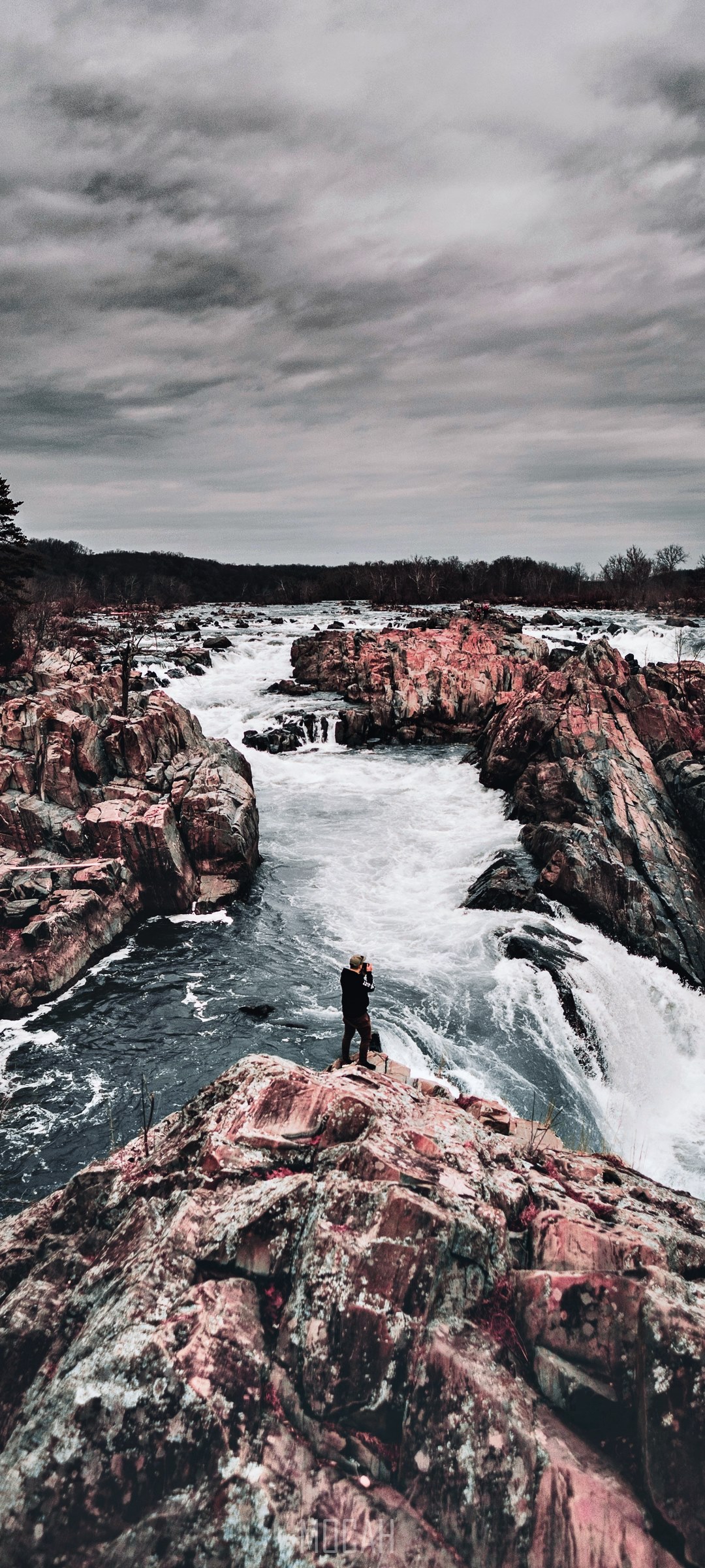 Person standing on rocks overlooking rapids HD Phone Wallpaper