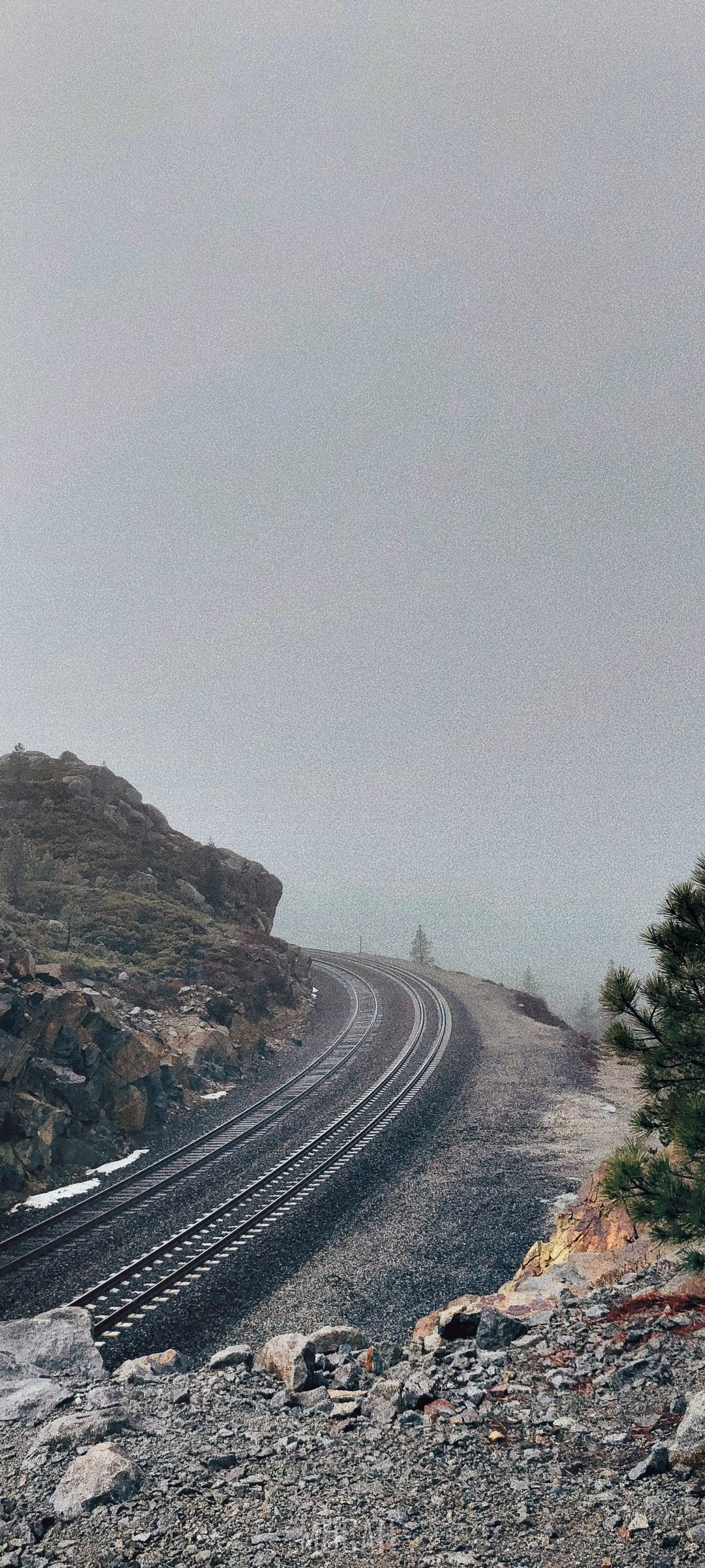 Railroad tracks curve through a foggy mountain landscape HD Phone Wallpaper