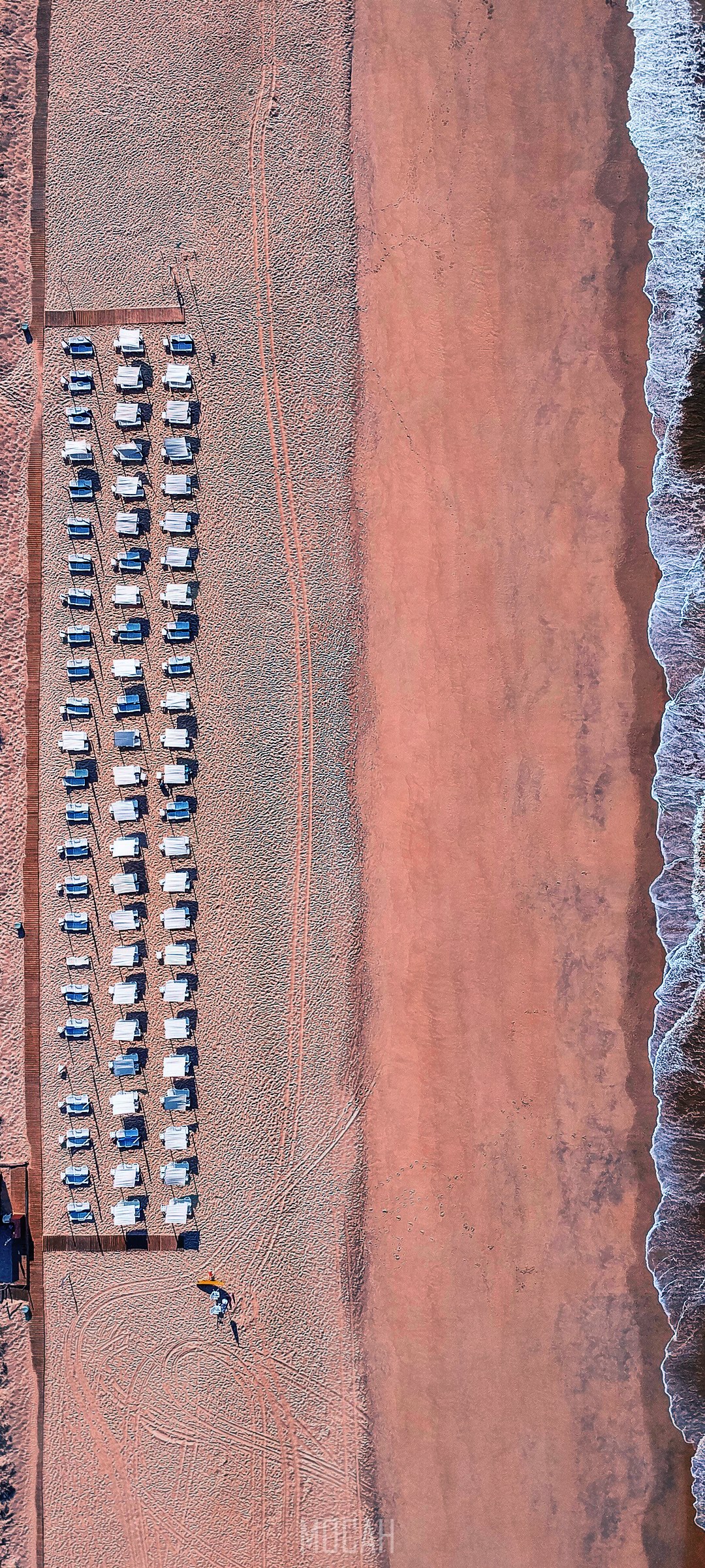 Aerial view of a beach with rows of white beach chairs and the ocean HD Phone Wallpaper