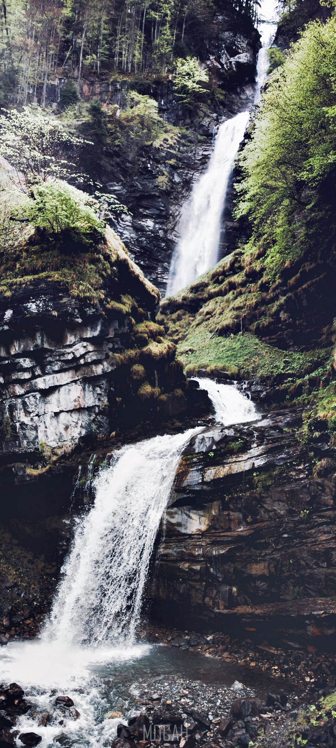 Waterfall cascading down a rocky, forested mountainside HD Phone Wallpaper