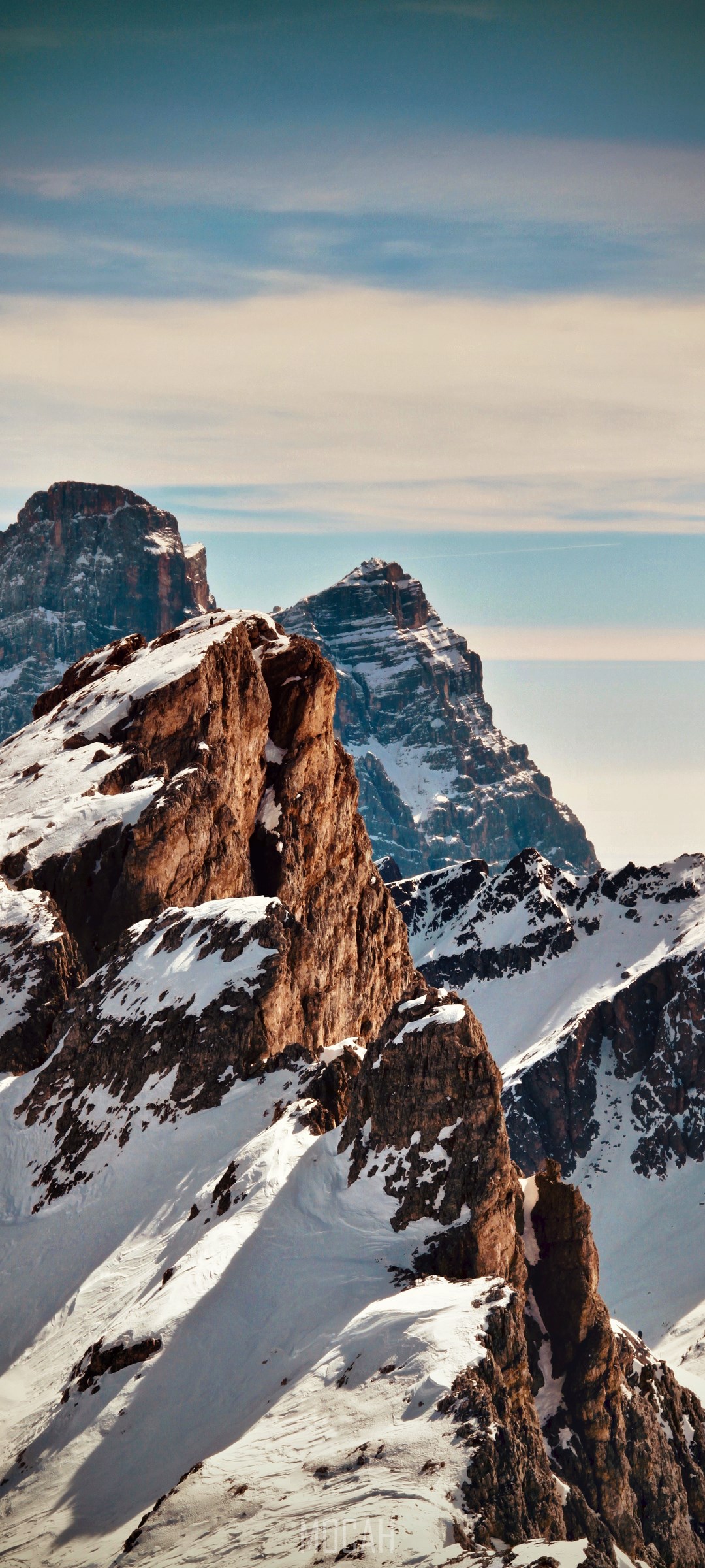 Snow-covered mountains and rocky peaks under a blue sky HD Phone Wallpaper