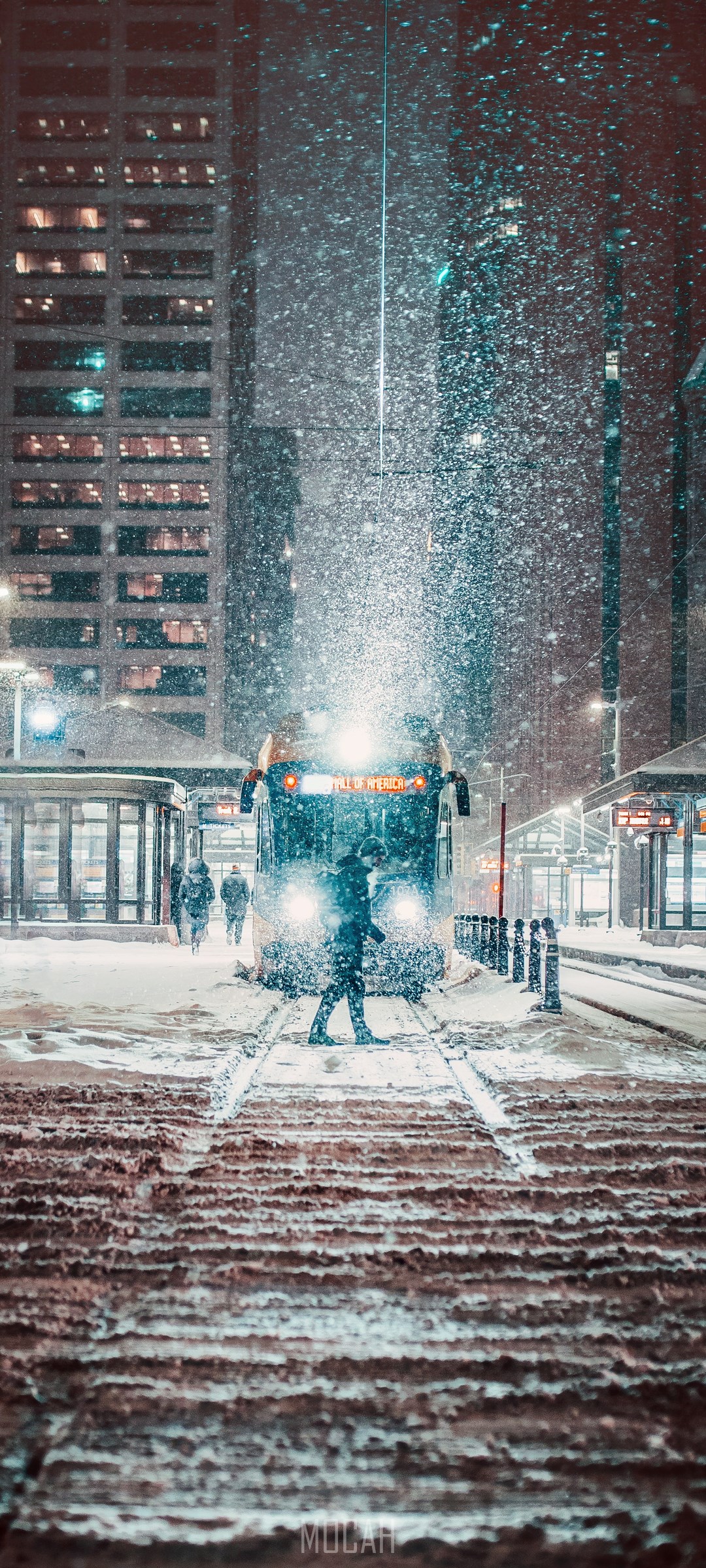 Person walking in snow towards a train at night HD Phone Wallpaper