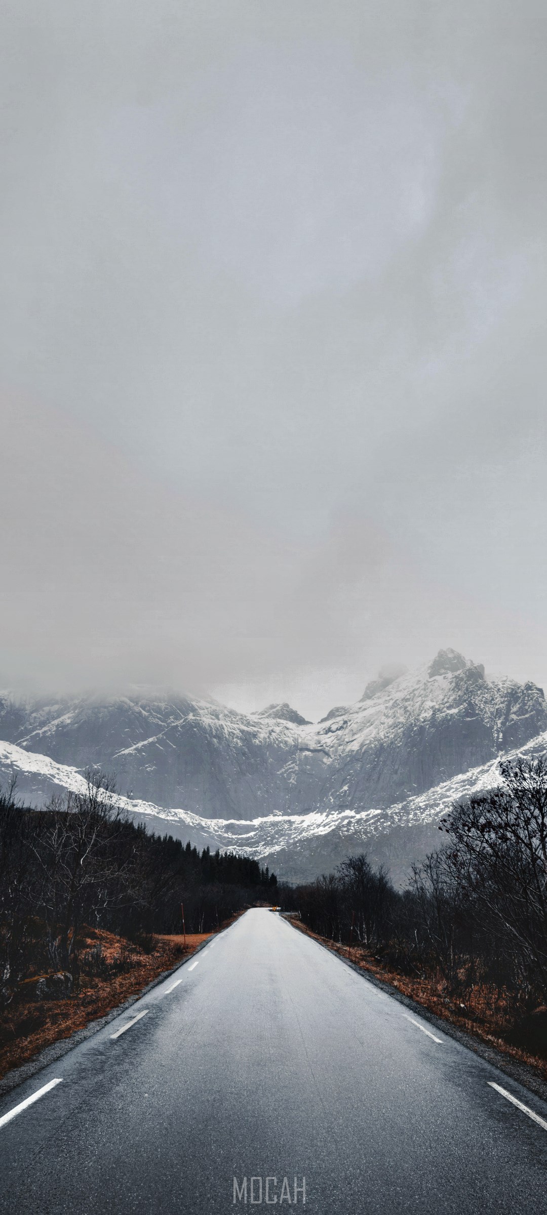 Road leading to snow-covered mountains under foggy sky HD Phone Wallpaper
