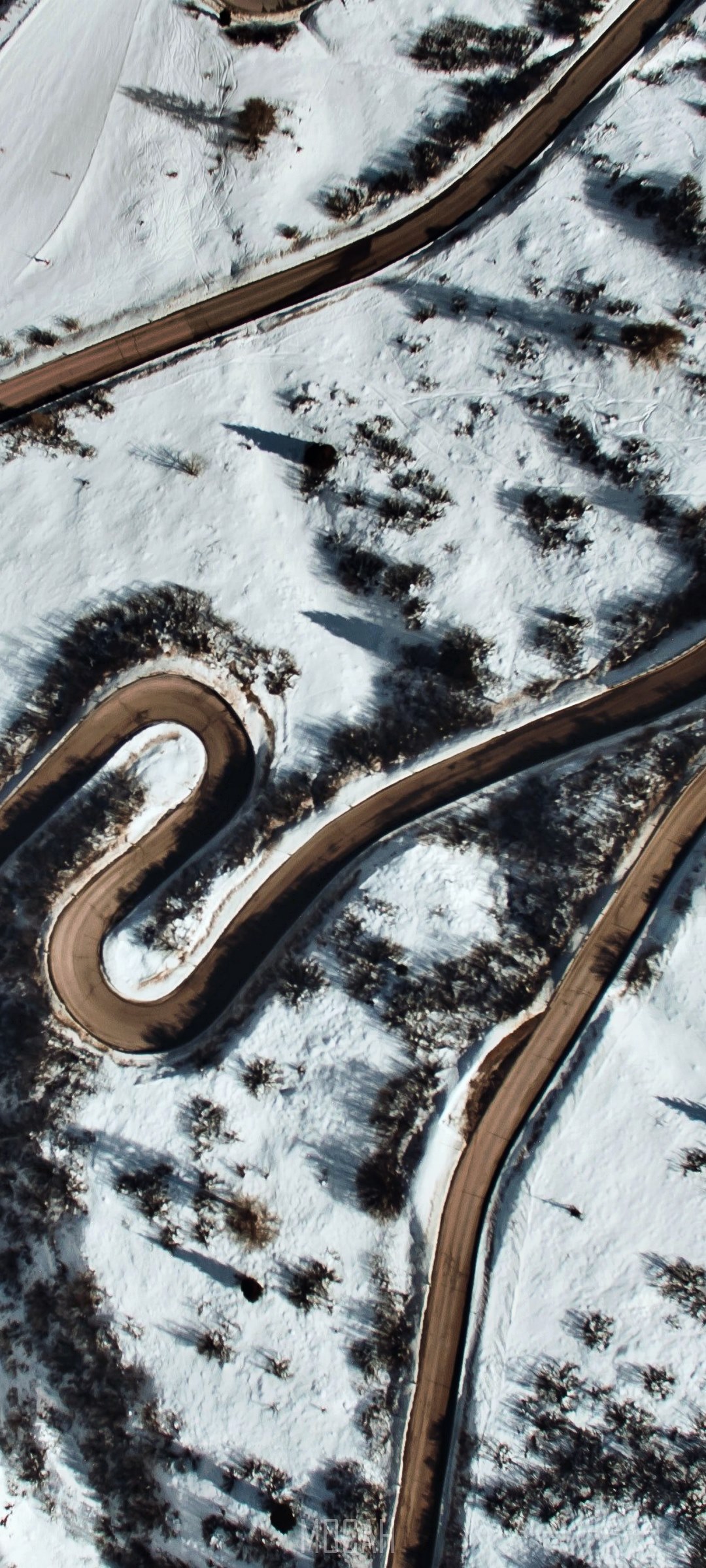 Aerial view of a winding road through a snowy landscape HD Phone Wallpaper