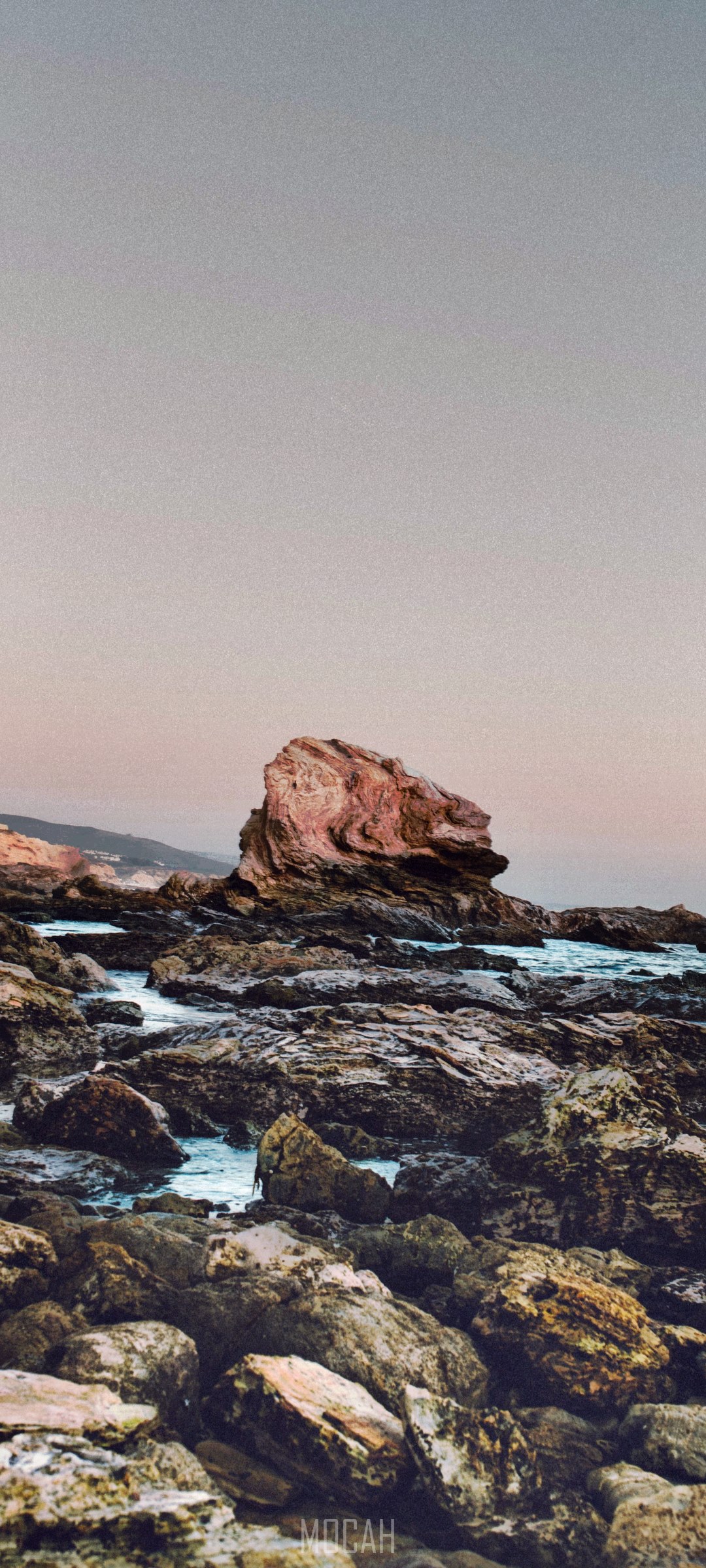 Rocky coastline with a large rock formation and ocean waves HD Phone Wallpaper