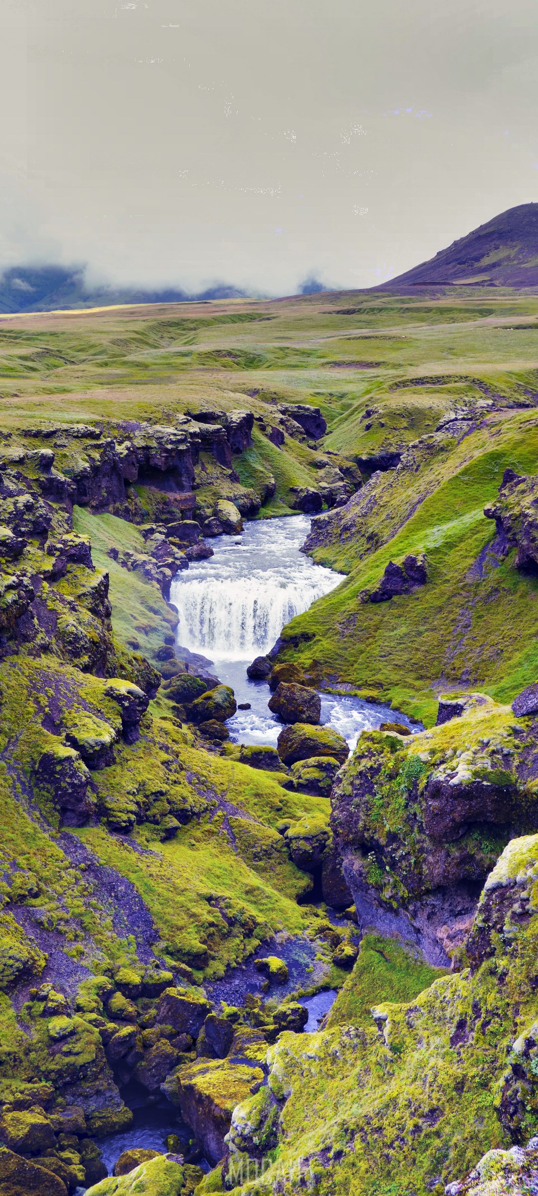 Waterfall in a moss-covered canyon with green hills HD Phone Wallpaper