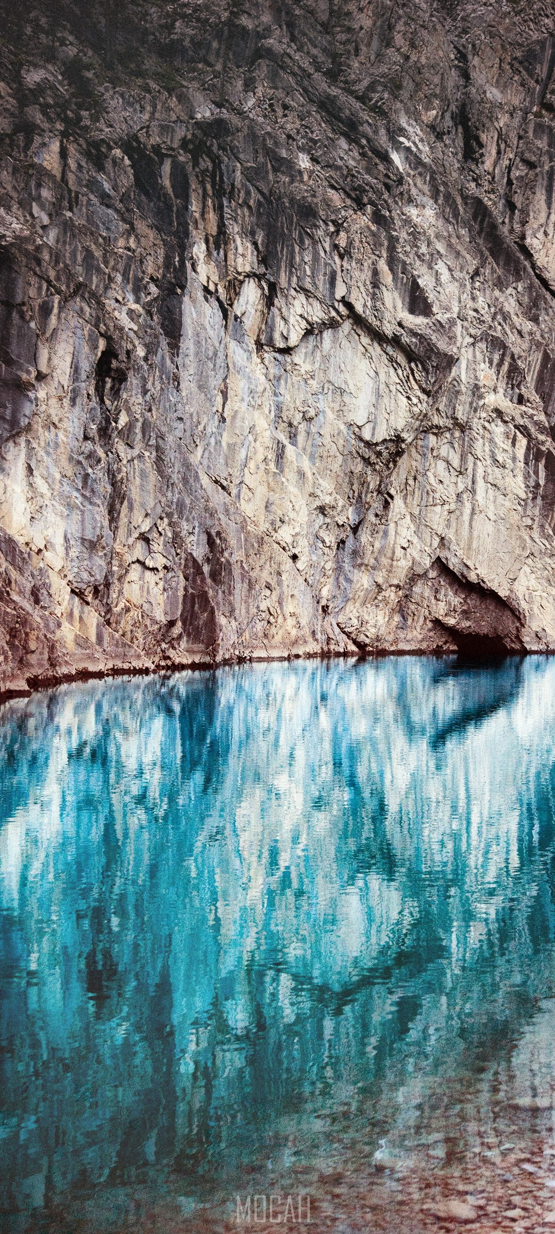 Rock cliff face reflected in blue water HD Phone Wallpaper