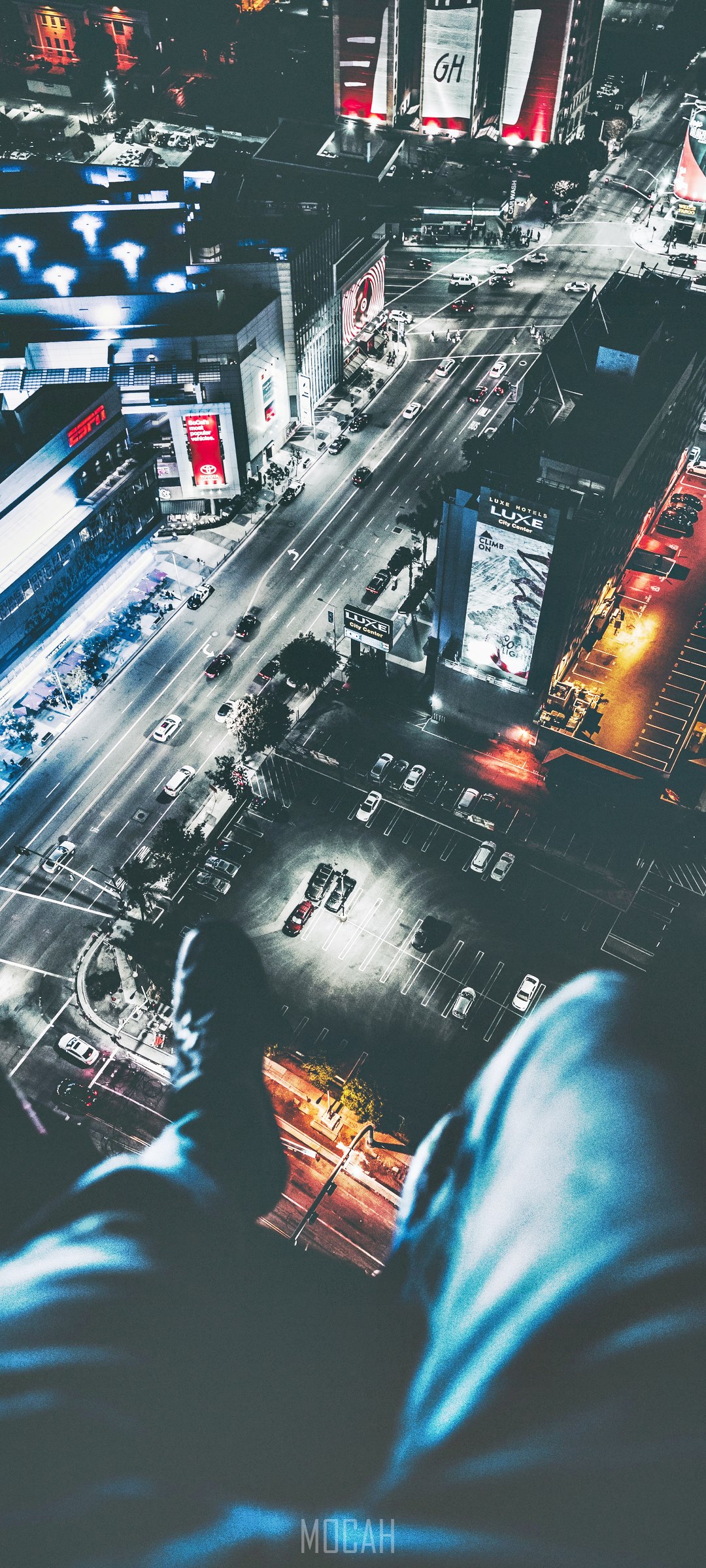 Person dangling legs off building roof overlooking city at night HD Phone Wallpaper
