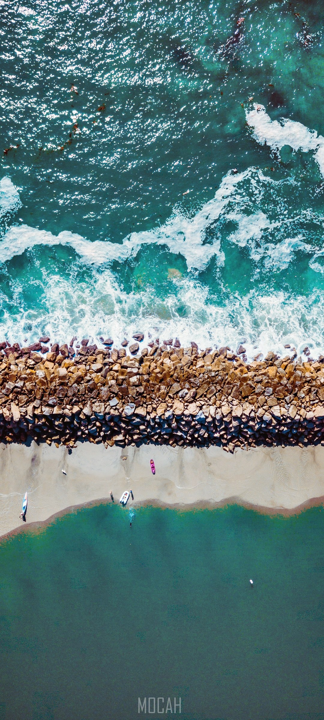 Aerial view of a rocky breakwater and beach with kayaks HD Phone Wallpaper