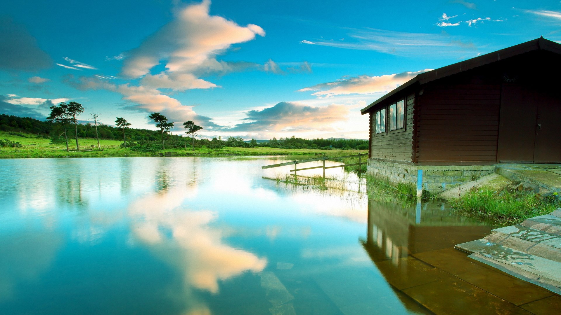 Wooden cabin by a reflective lake at sunset HD Wallpaper