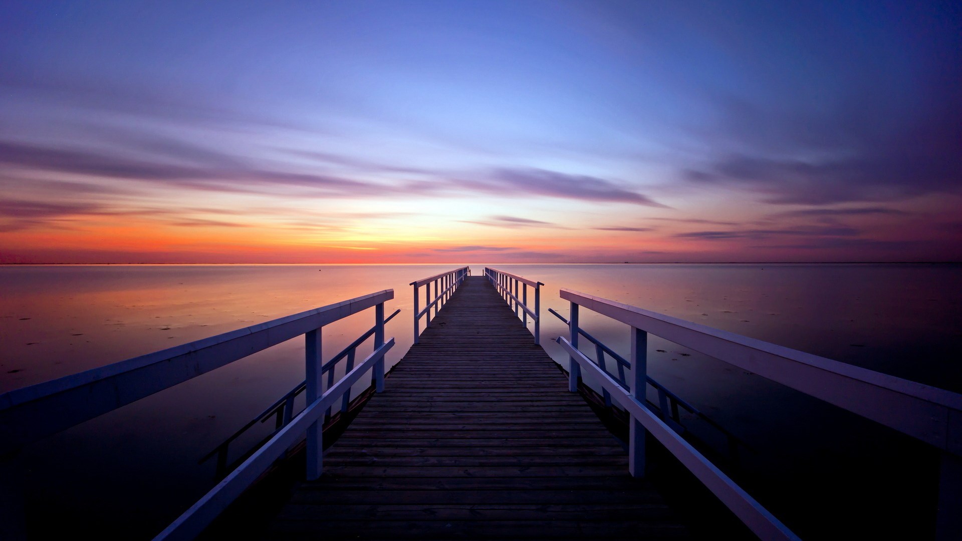 Wooden pier over calm water at sunset HD Wallpaper