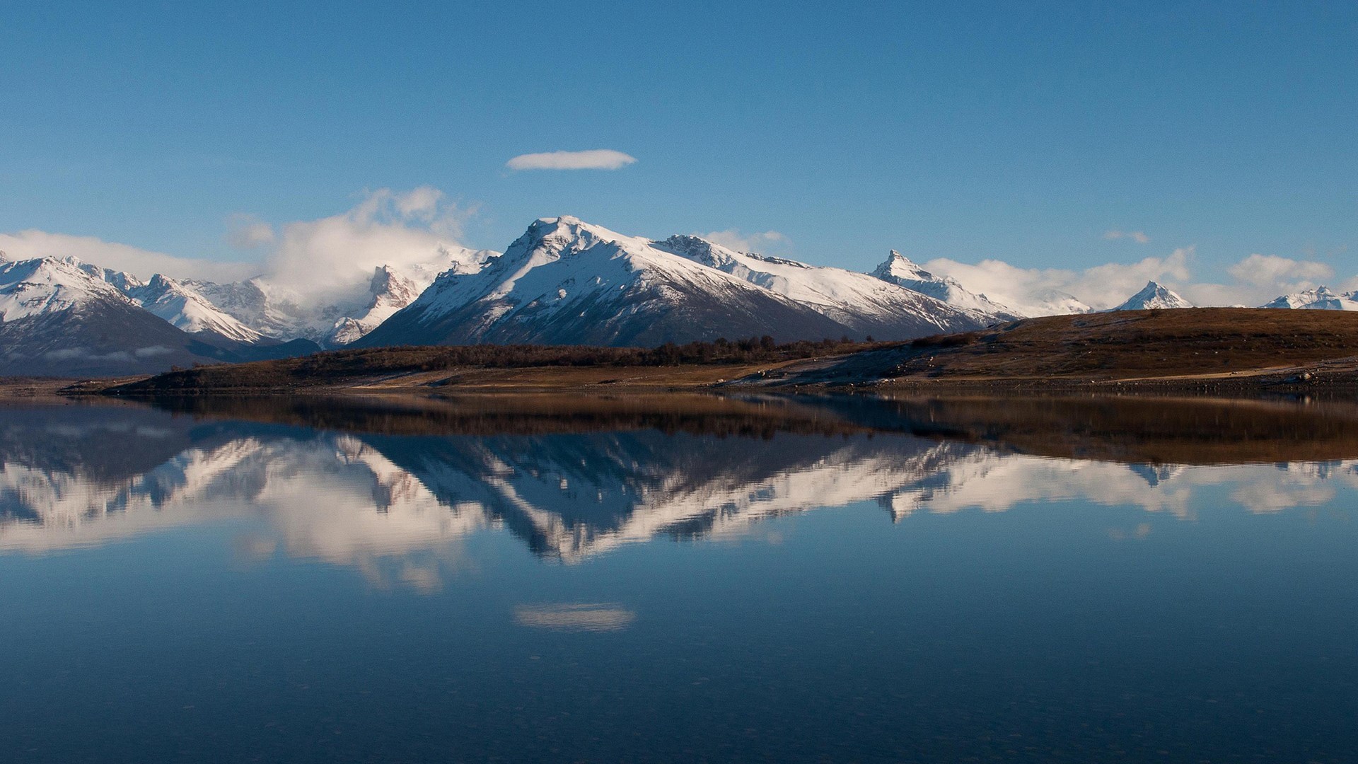 Snow-capped mountains reflected in a calm lake HD Wallpaper