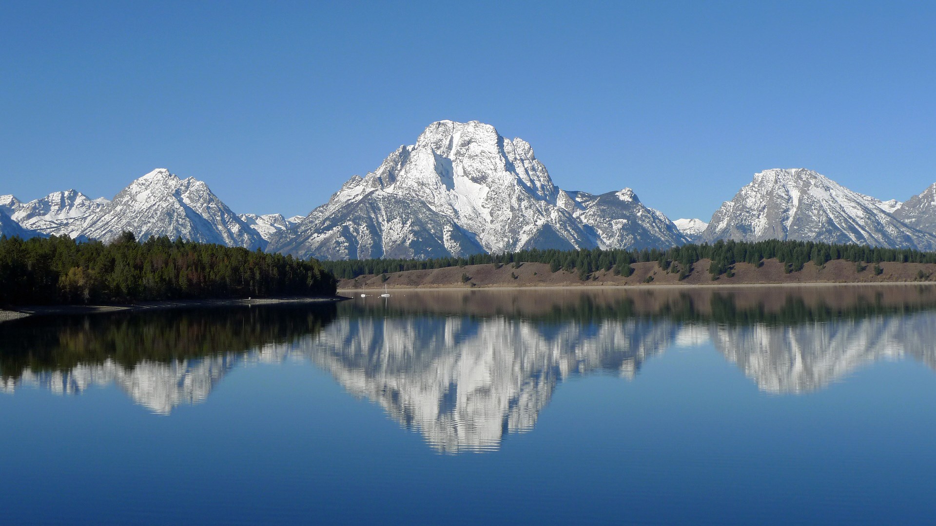 Snow-capped mountains reflected in a calm lake HD Wallpaper