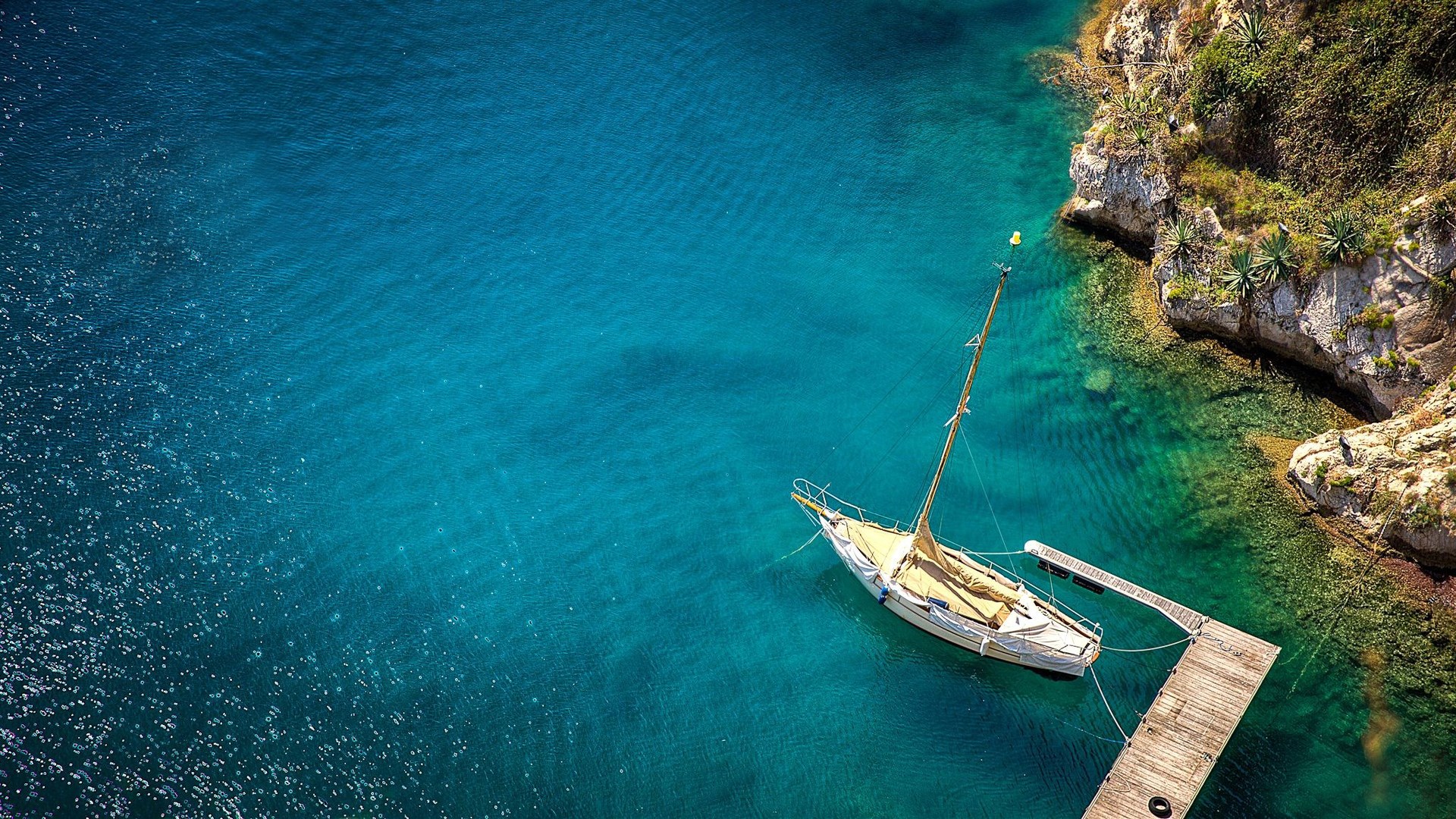 Sailboat moored at a wooden dock near a rocky coast HD Wallpaper