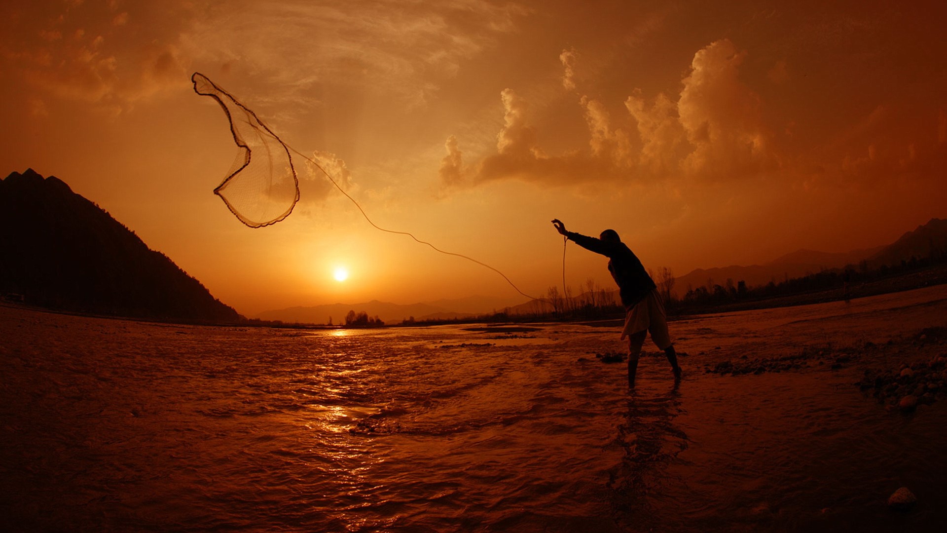 Fisherman casting net at sunset over river HD Wallpaper