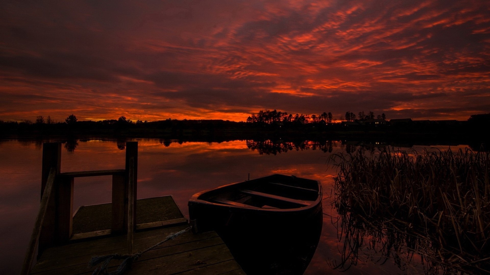 Boat docked at pier during a fiery sunset HD Wallpaper