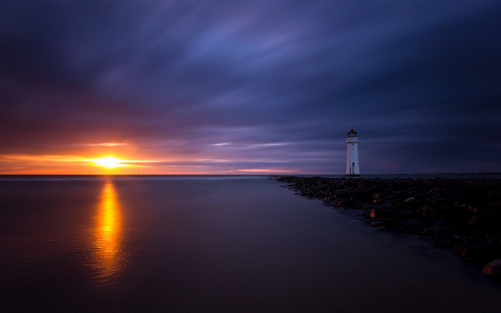 Lighthouse at sunset with reflection on water HD Wallpaper