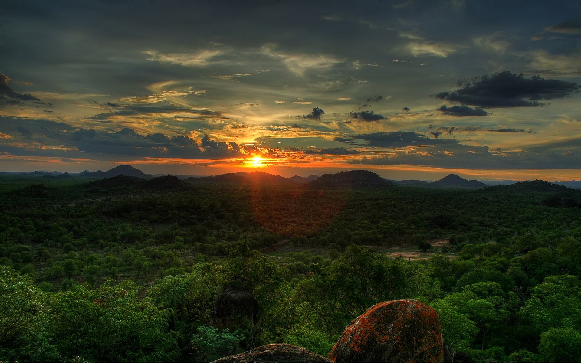 Sunset over a green, hilly landscape with dramatic clouds HD Wallpaper