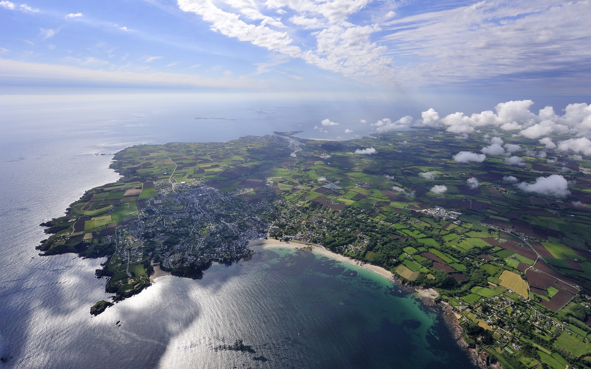 Aerial view of a coastal town and green fields HD Wallpaper