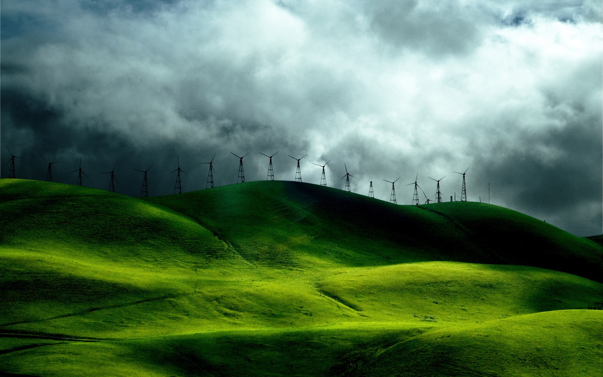 Wind turbines on green hills under stormy clouds HD Wallpaper