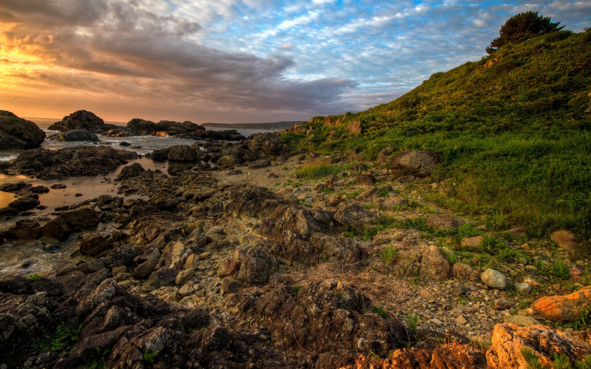 Rocky coastline with grassy hill at sunset HD Wallpaper