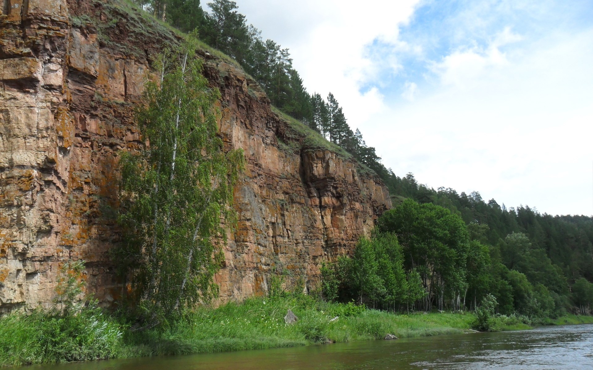 Rocky cliff face overlooking a river with trees HD Wallpaper