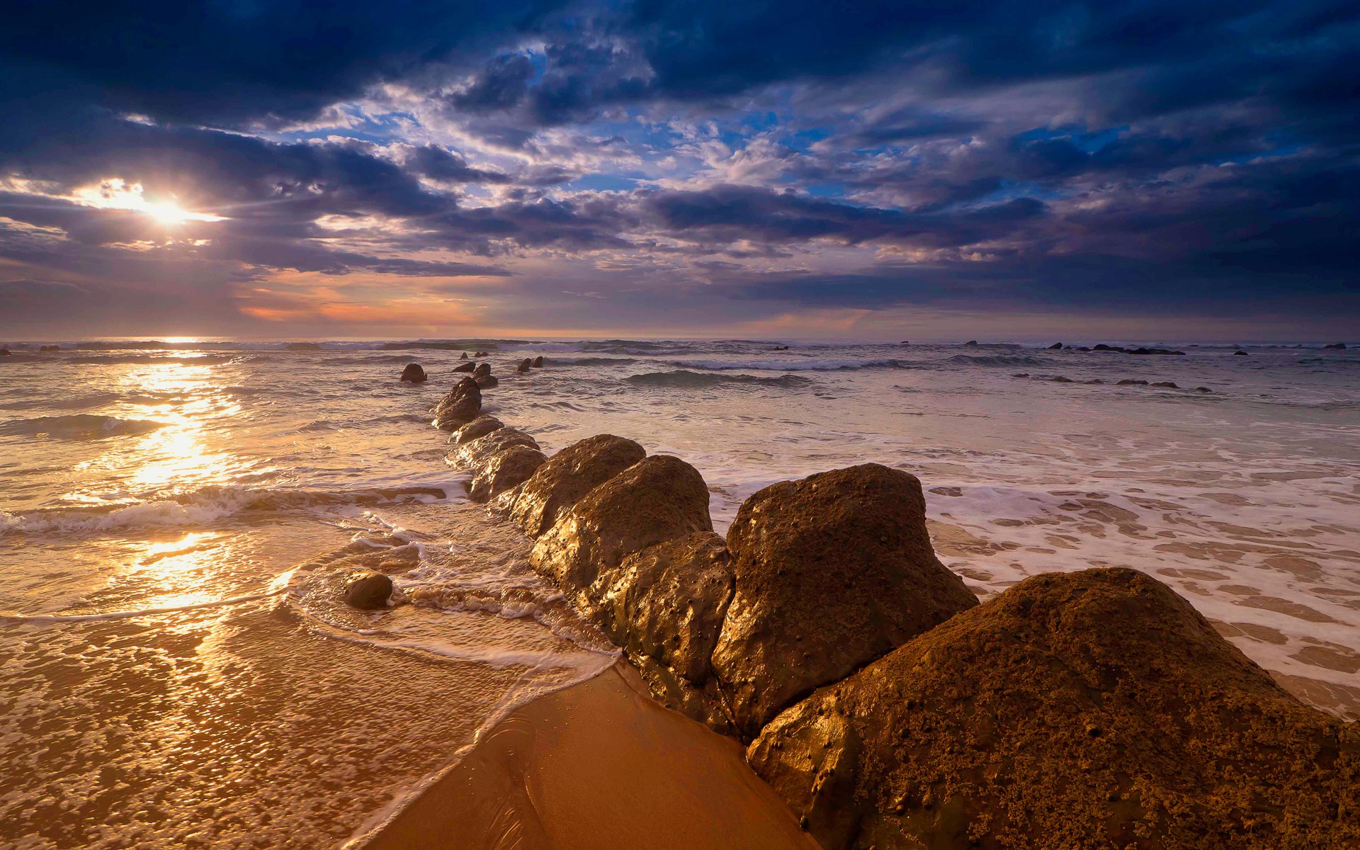 Ocean waves crash on a rocky shore at sunset HD Wallpaper