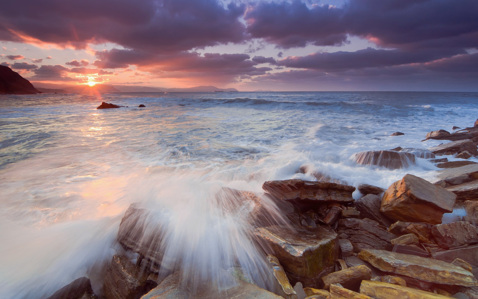 Waves crashing on rocky shore at sunset HD Wallpaper
