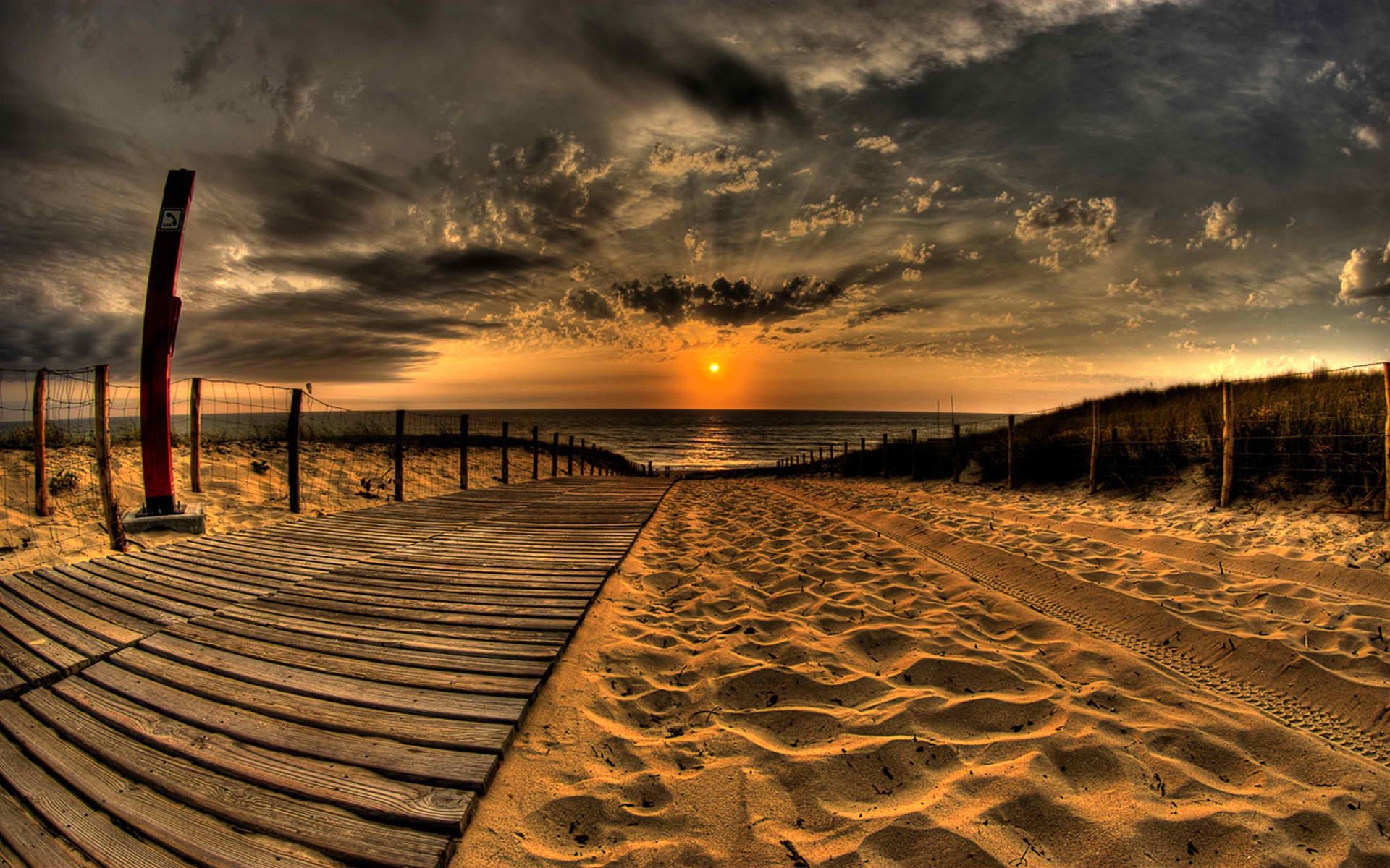 Wooden boardwalk and sandy path leading to the ocean at sunset HD Wallpaper