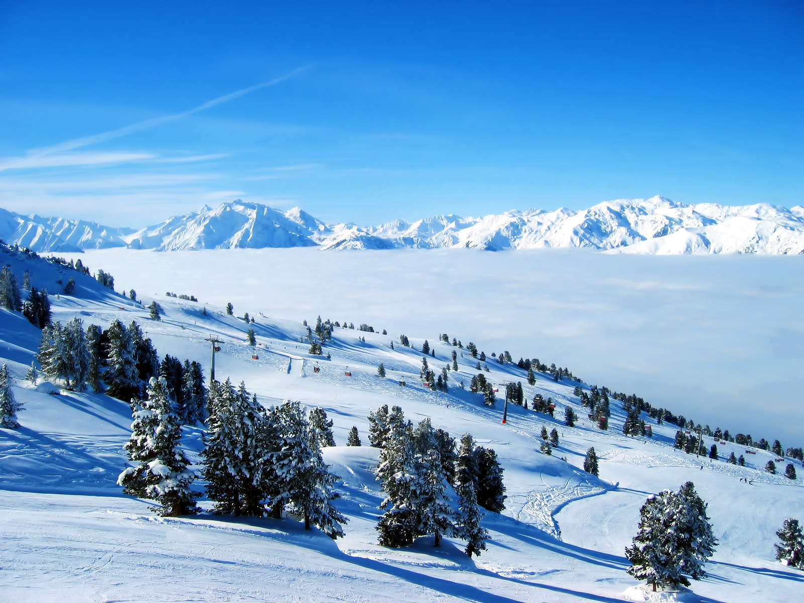 Snowy mountain ski resort with clouds below HD Wallpaper