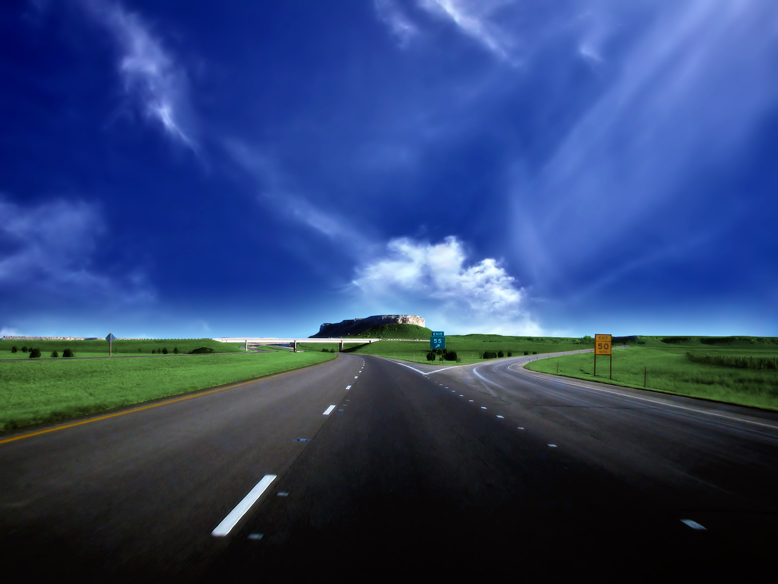 Road splitting with a mesa in the distance under a blue sky HD Wallpaper