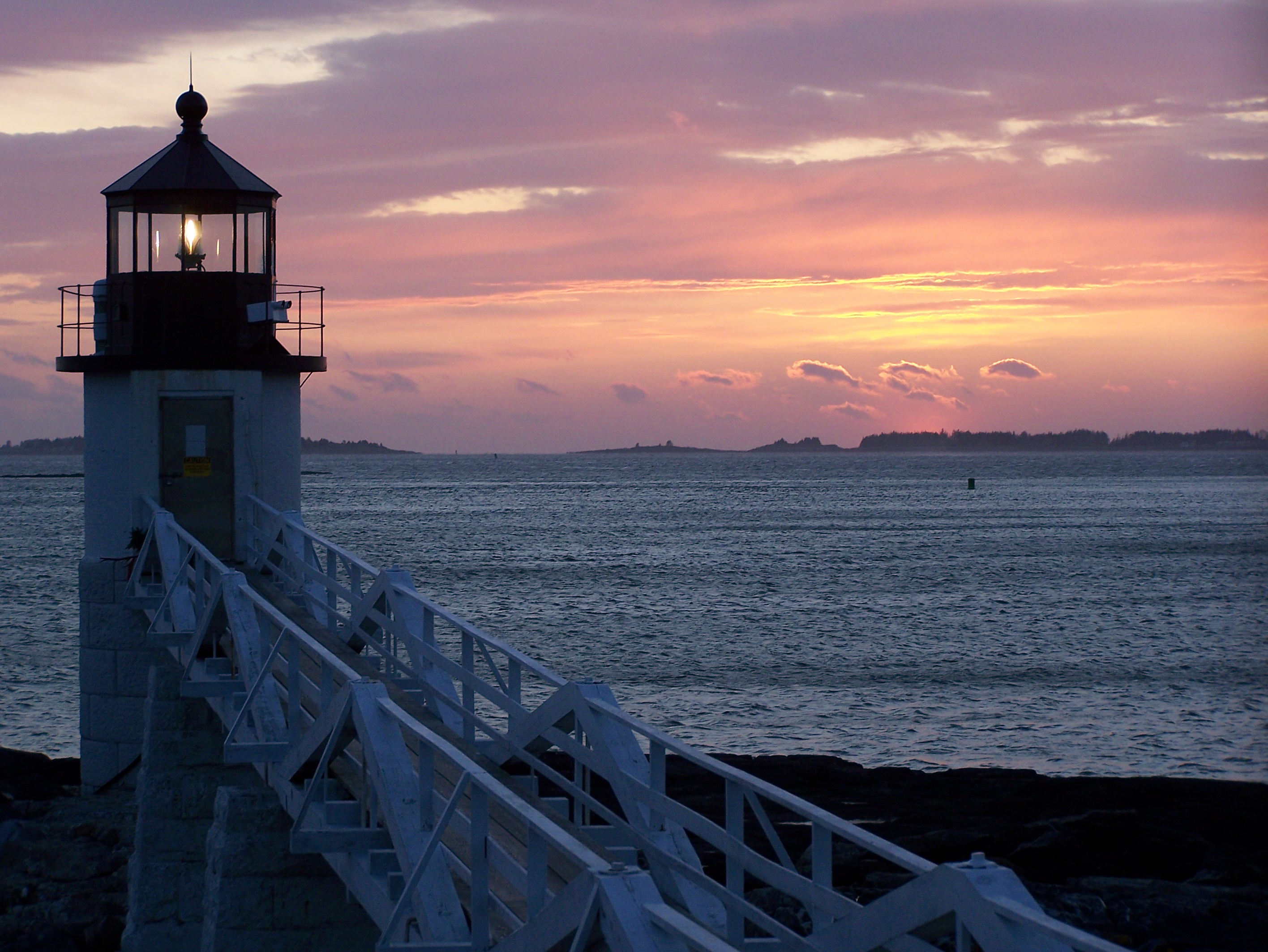 Lighthouse at sunset over the ocean HD Wallpaper