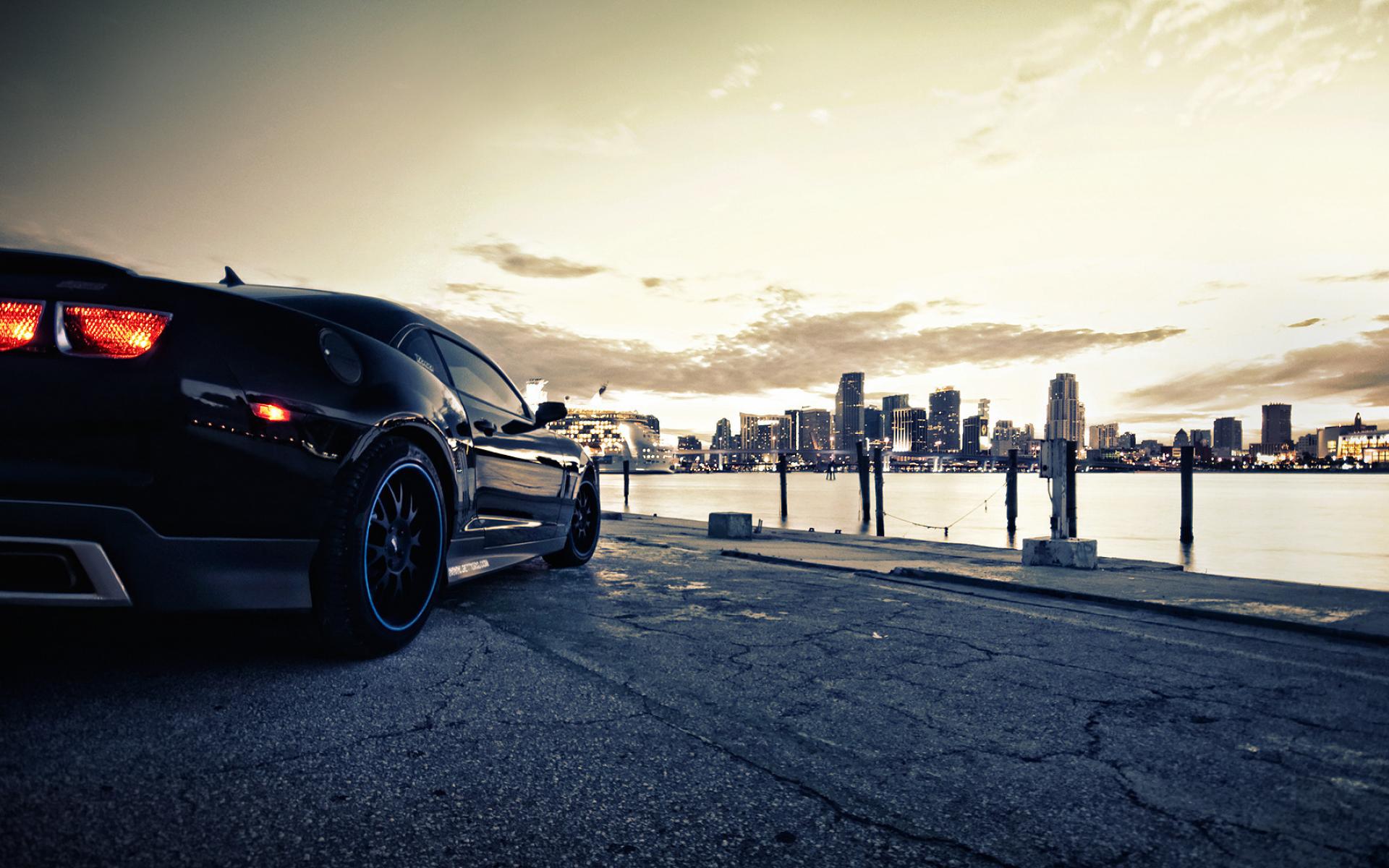 Black Chevrolet Camaro parked by Miami skyline at sunset HD Wallpaper